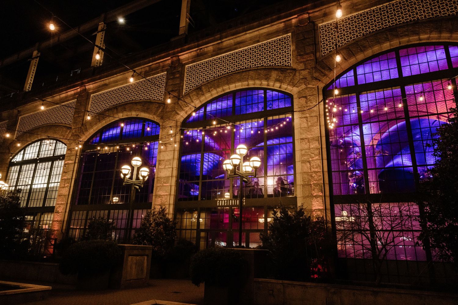 Stunning wedding venue exterior at night with purple and blue illuminated arched windows.
