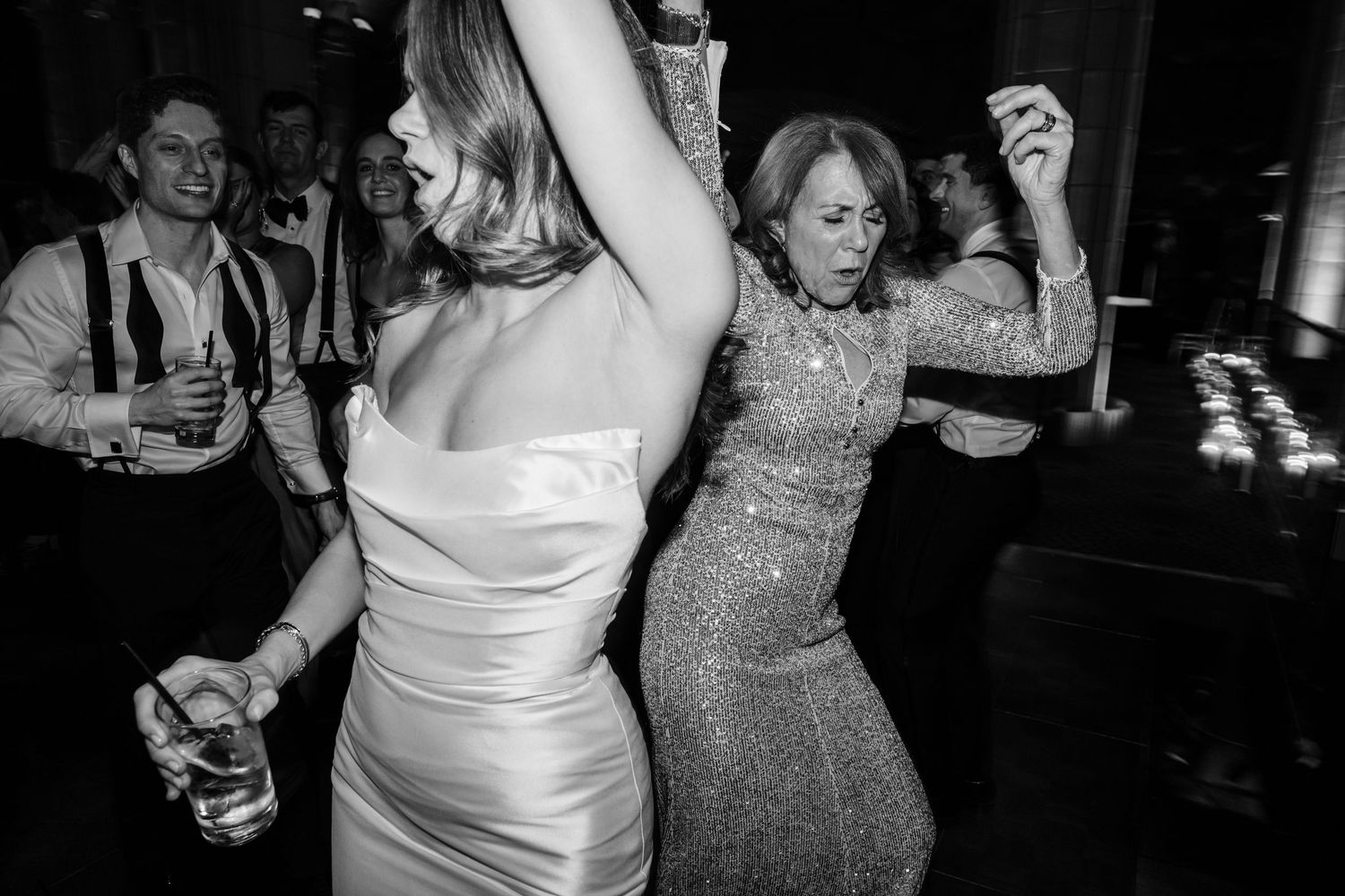 Black and white photo of bride and guest dancing energetically at a wedding reception party.