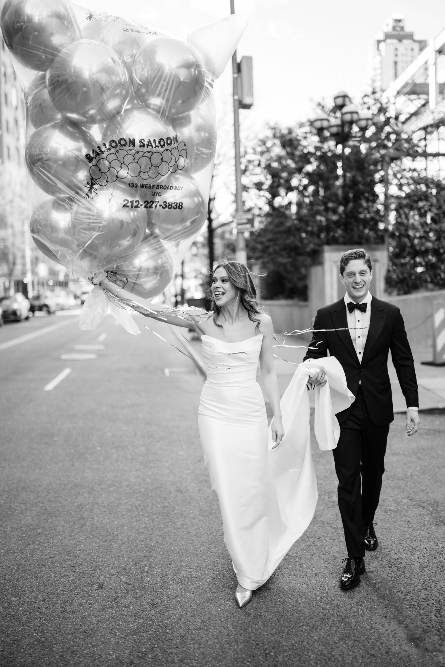 Black and white photo of newlyweds walking with Balloon Saloon balloons on a NYC street.