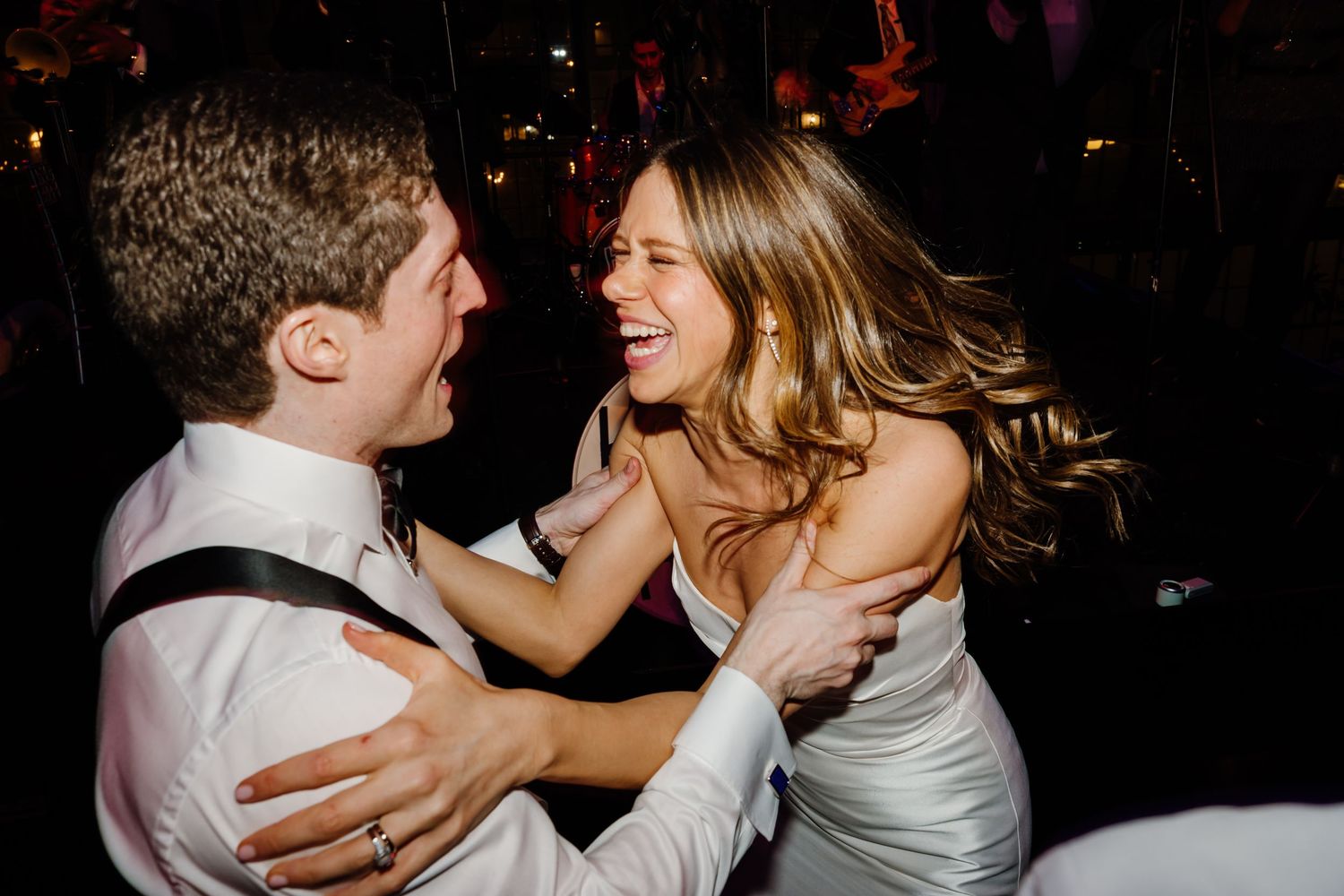 Bride and groom laughing joyfully together on the dance floor at wedding reception.