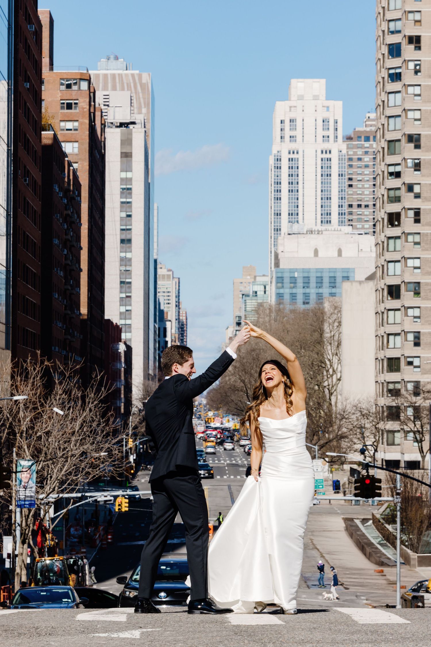 Bride and groom dancing in the middle of a New York City street with skyscrapers in the background.