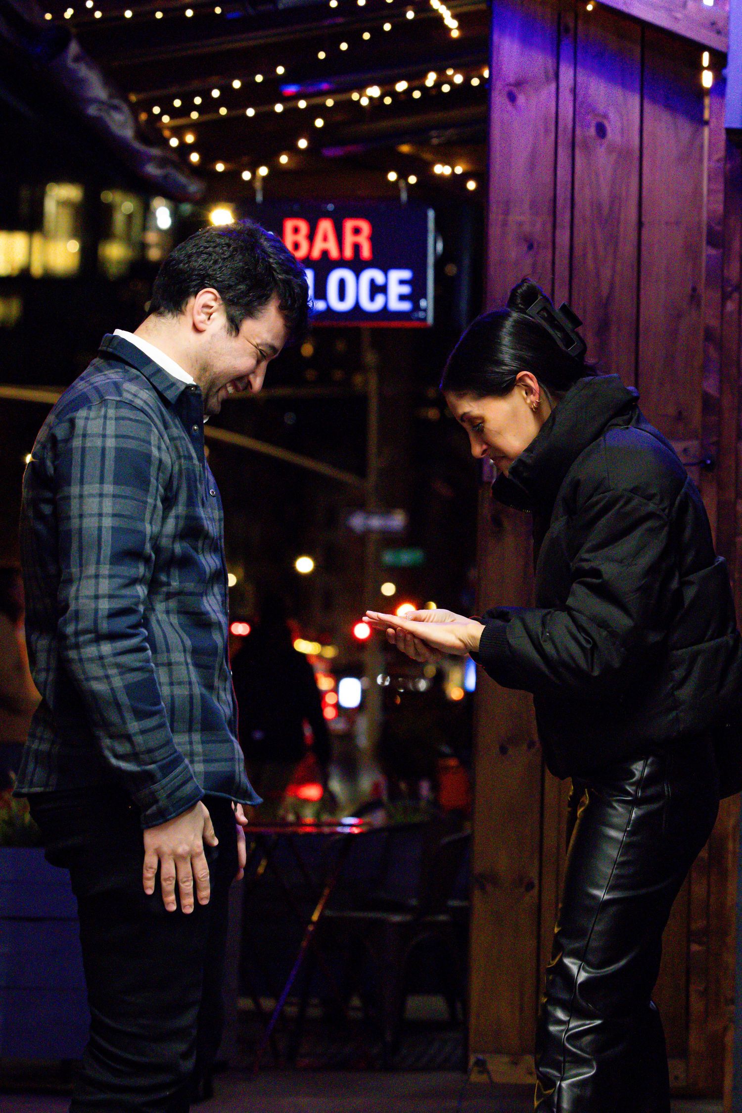 Newly engaged couple examining engagement ring outside Bar Veloce bar in New York City.