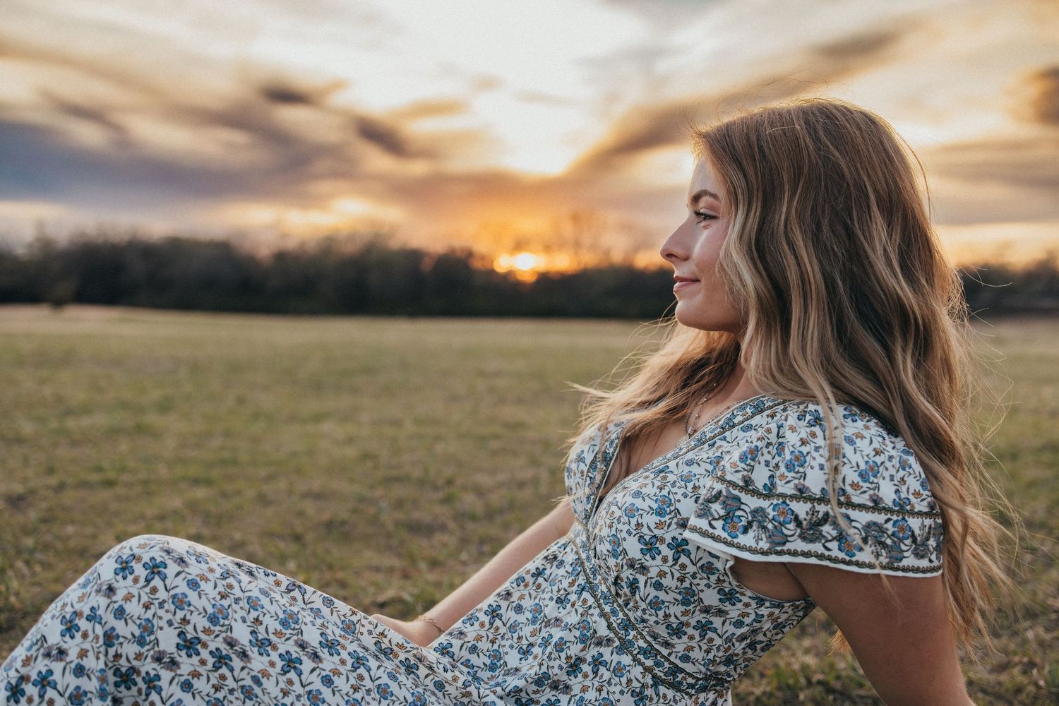 Floral dress silhouette against dramatic sunset sky with golden clouds.