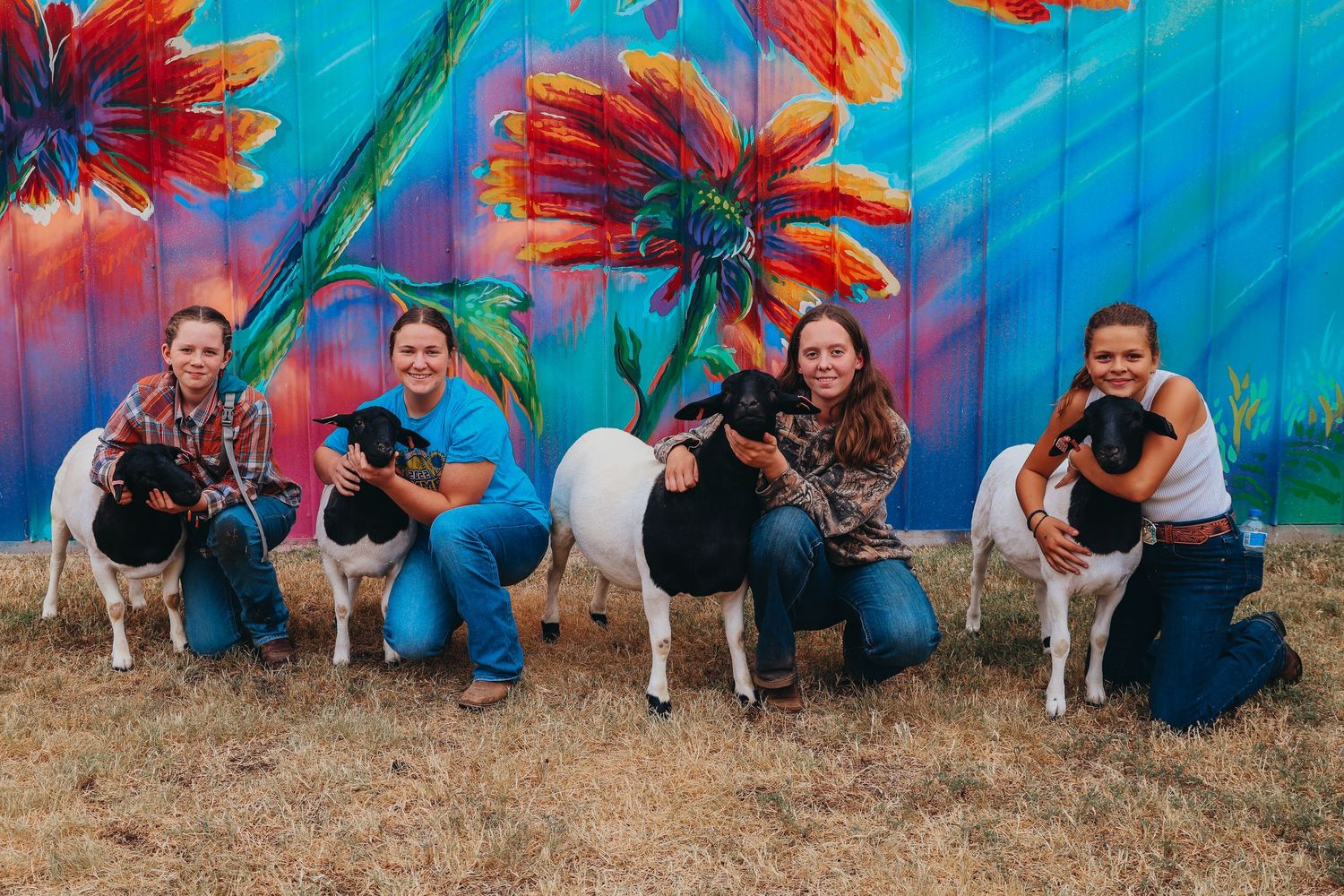 Sequence of people in blue shirts bending down in synchronized poses against a colorful mural backdrop.