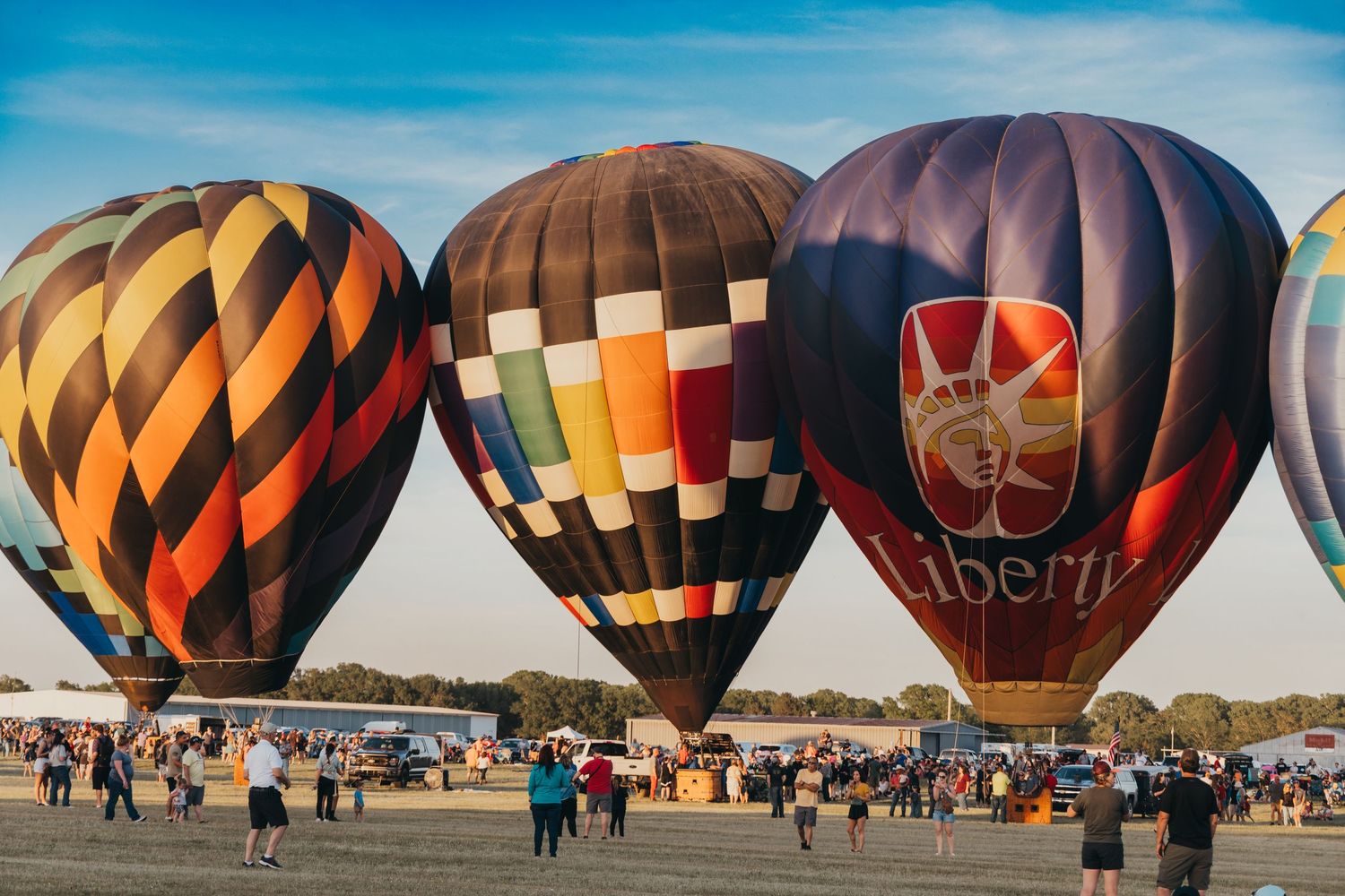 Colorful hot air balloons with geometric patterns displayed at an outdoor festival.