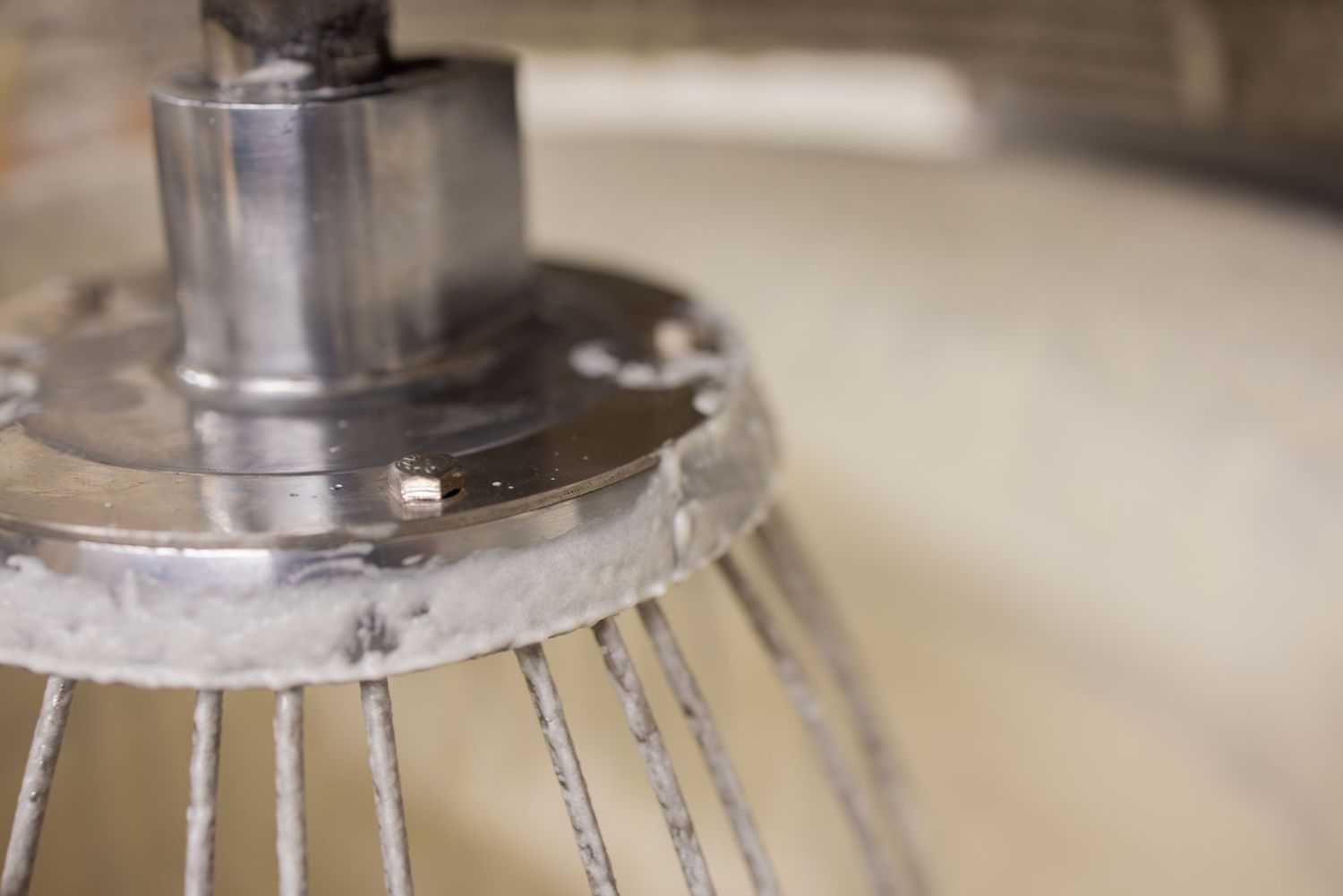 Close-up detail of industrial mixing equipment with metal whisk attachments.