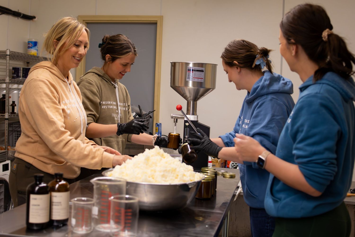 People working together in a commercial kitchen preparing food with a large mixing bowl.