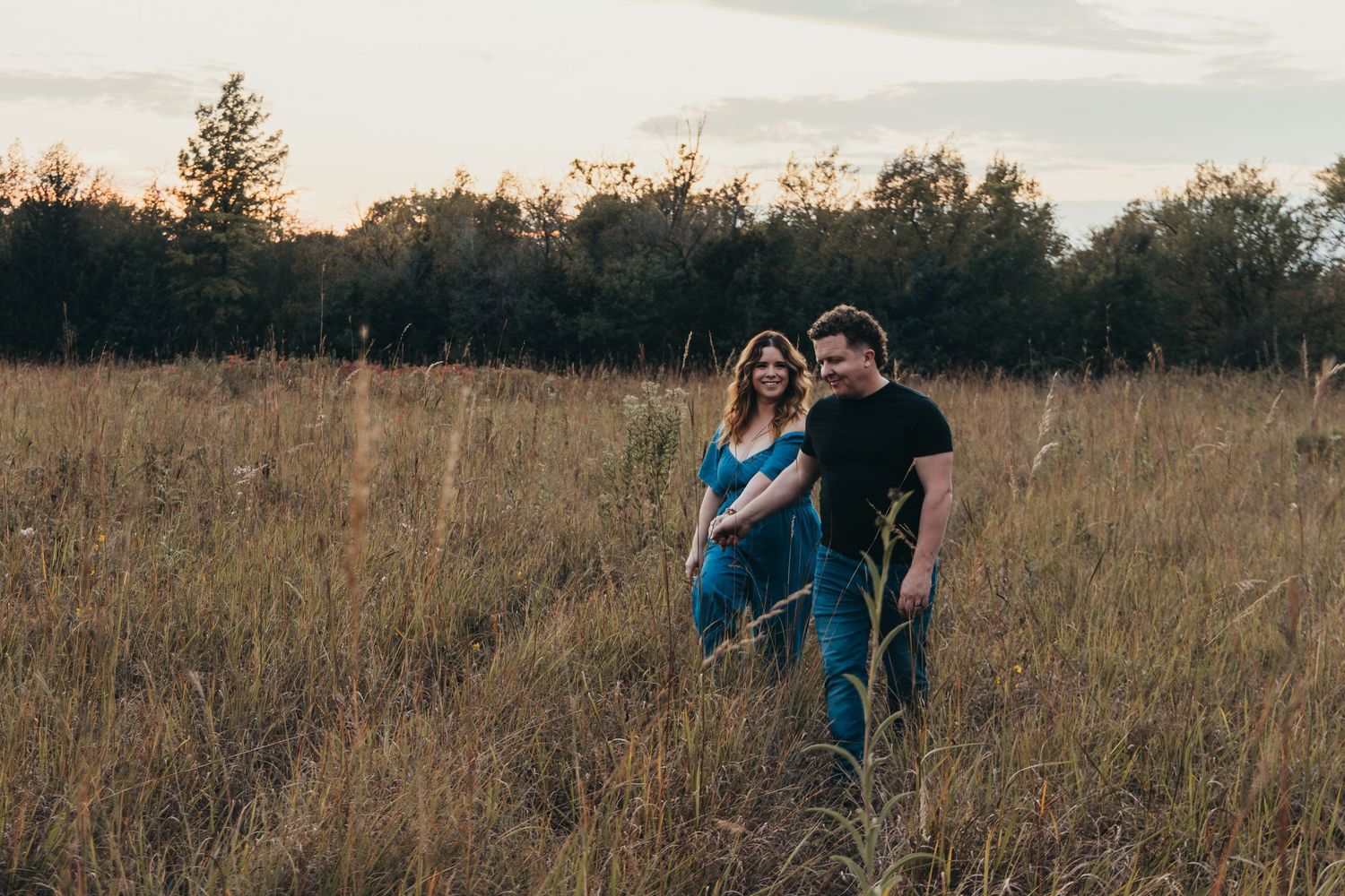 Silhouettes of people dancing and playing in a golden field at sunset.