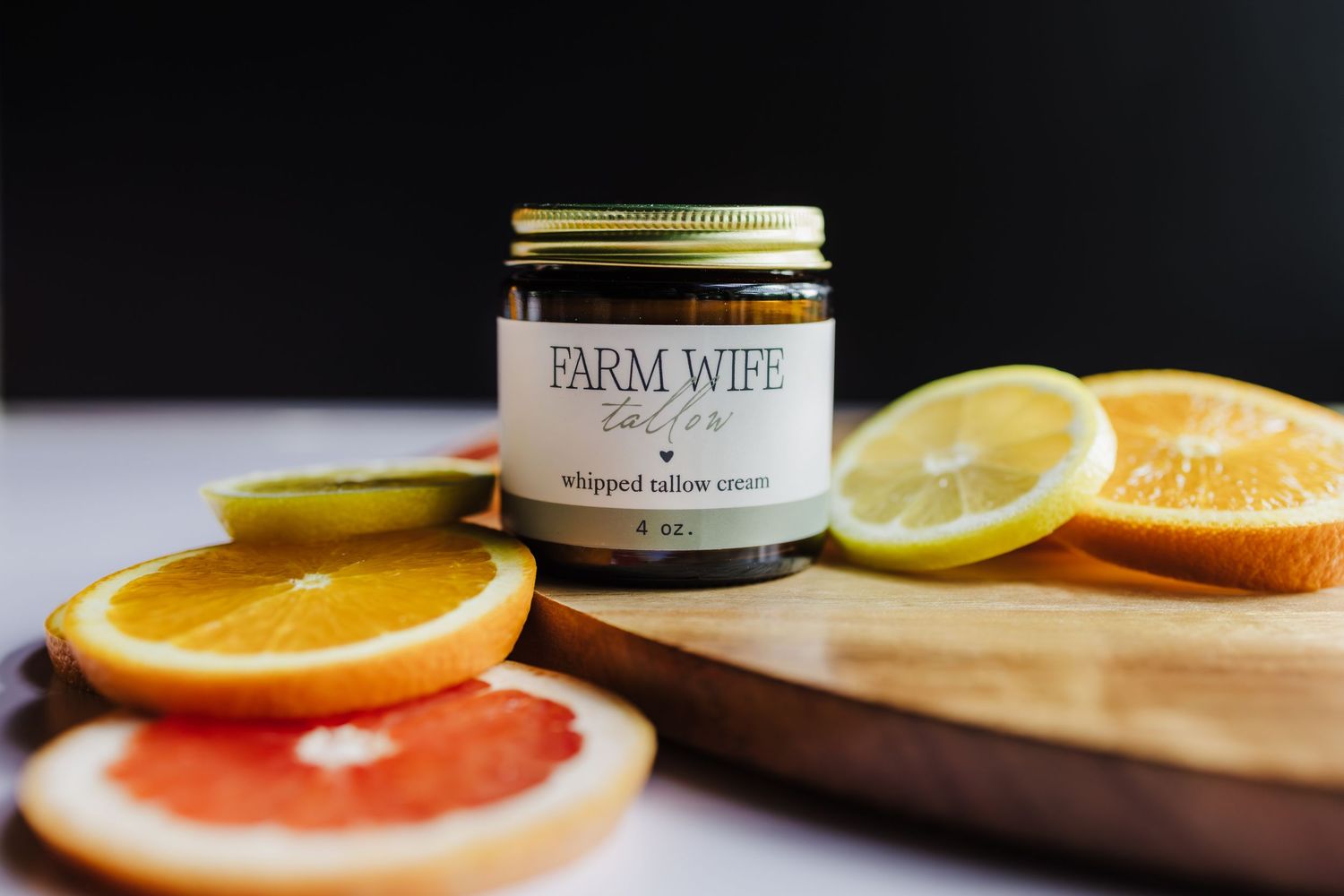 A jar of Farm & Wild honey on a wooden board with sliced citrus fruits including orange, lemon and grapefruit.