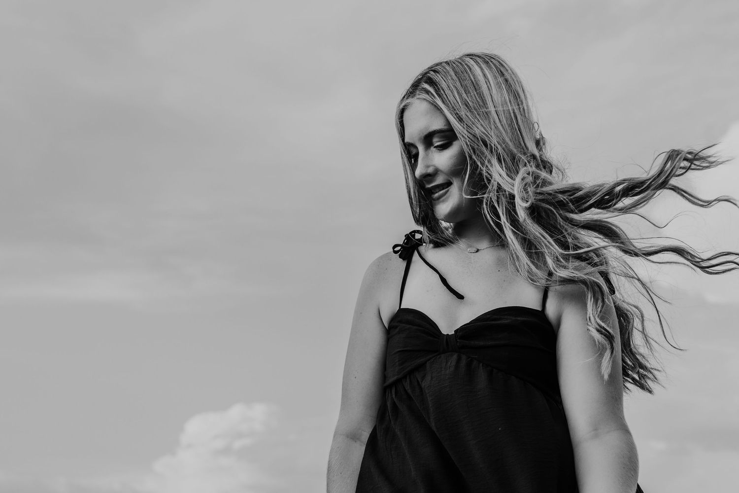 A series of black and white editorial style fashion photos showing a model posing outdoors with windswept hair.