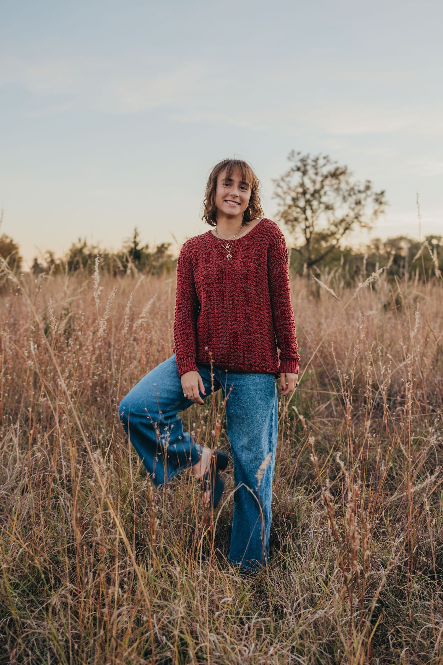 A series of photos showing someone in a burgundy sweater and jeans walking through a field of tall grass at sunset.