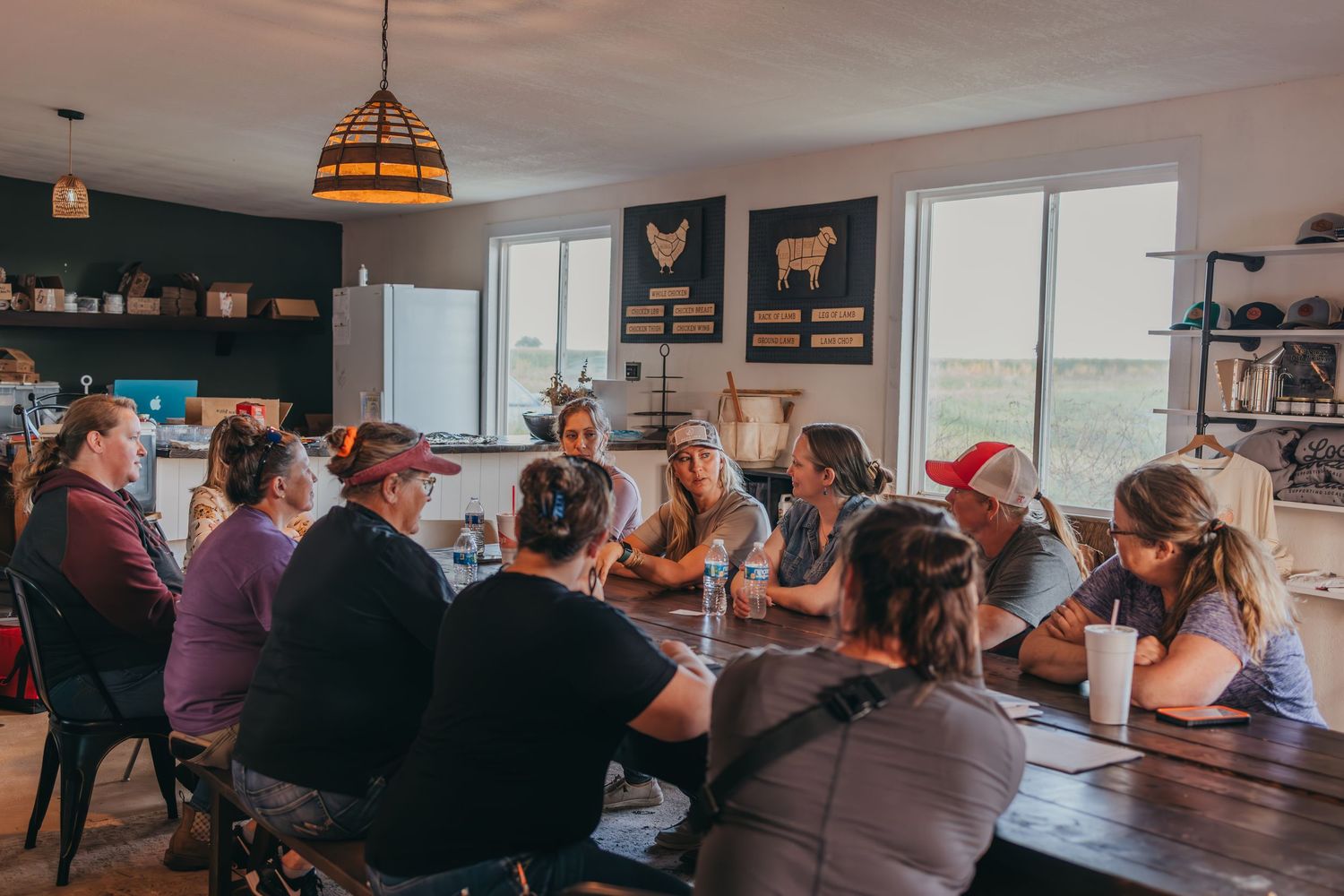 Group gathered around a long dining table in rustic room with farmhouse decor.