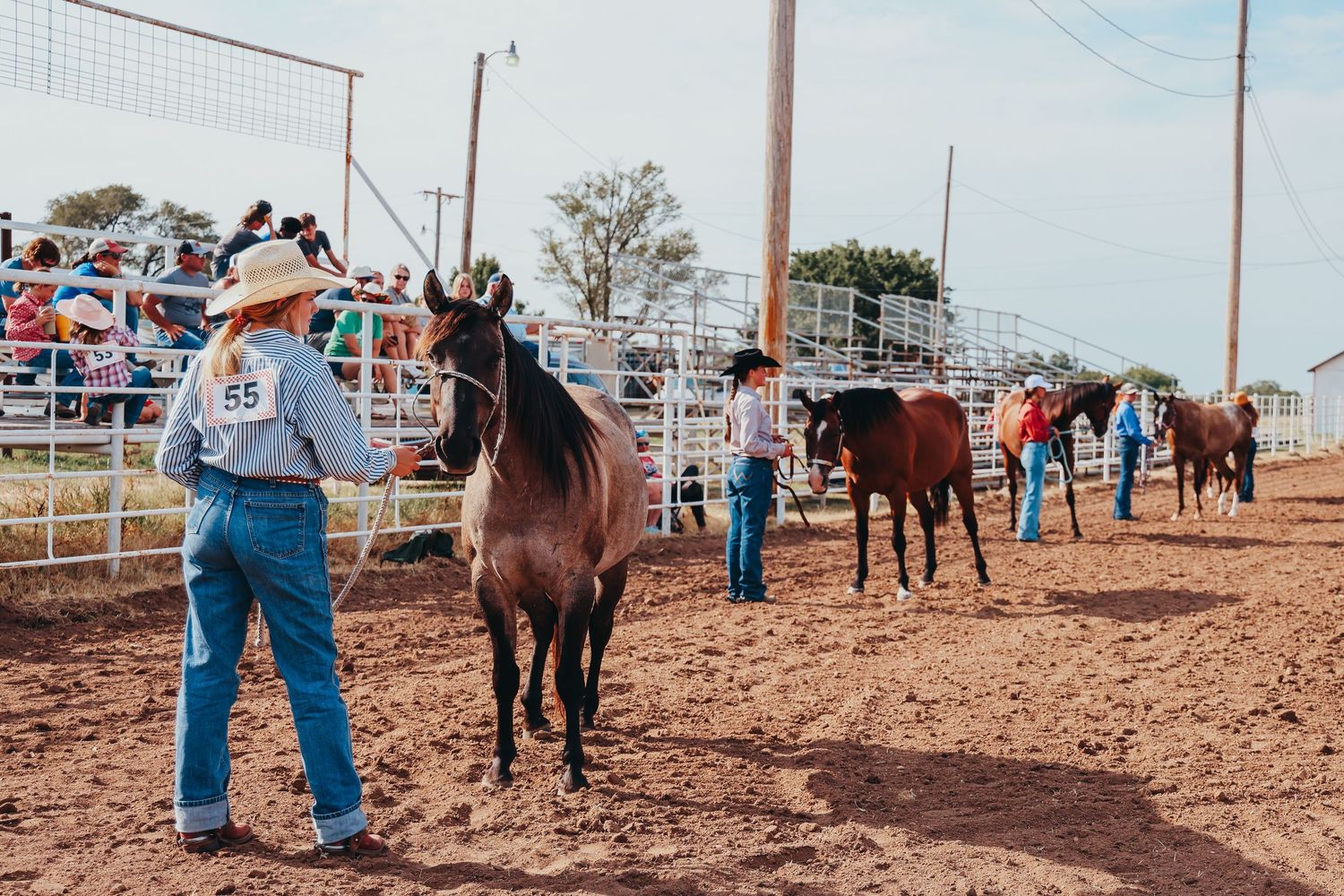 Cowboys leading horses in an arena during a rodeo event.