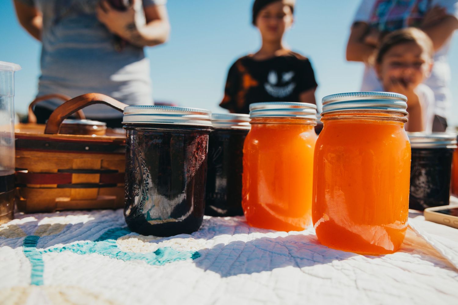 Rows of glowing orange preserves in glass mason jars lined up on wooden shelves in bright natural light.