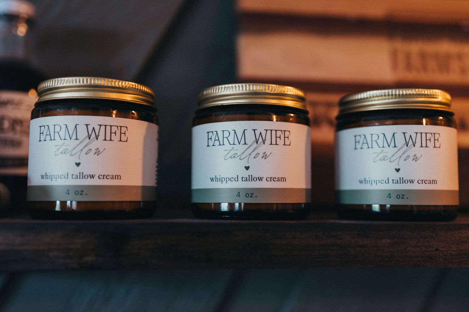 Three mason jars of Farm Wife branded products lined up on a wooden shelf.