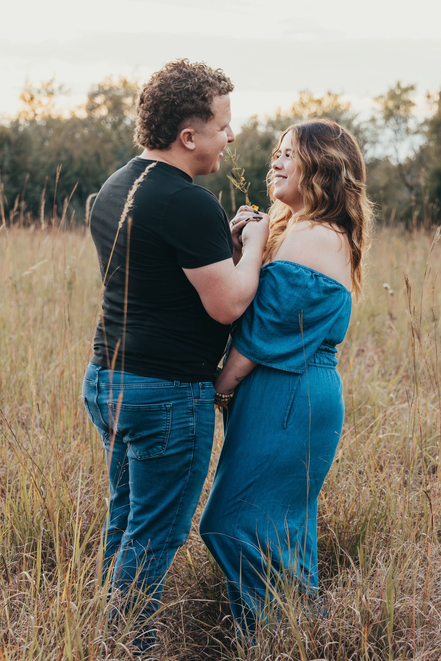 A couple shares an intimate moment while standing together in a golden field at sunset.