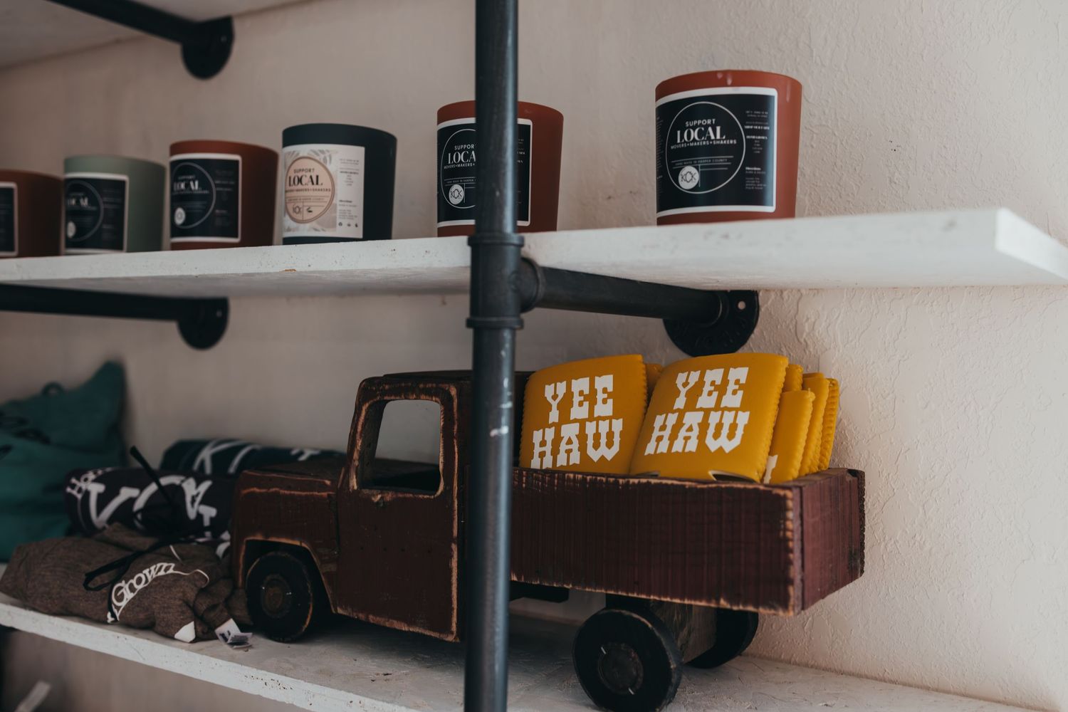 Vintage toy truck display on white shelving with decorative jars and candles arranged on industrial style brackets.