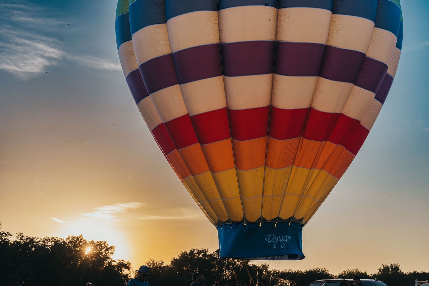 Hot air balloon with colorful stripes silhouetted against a golden sunset sky.