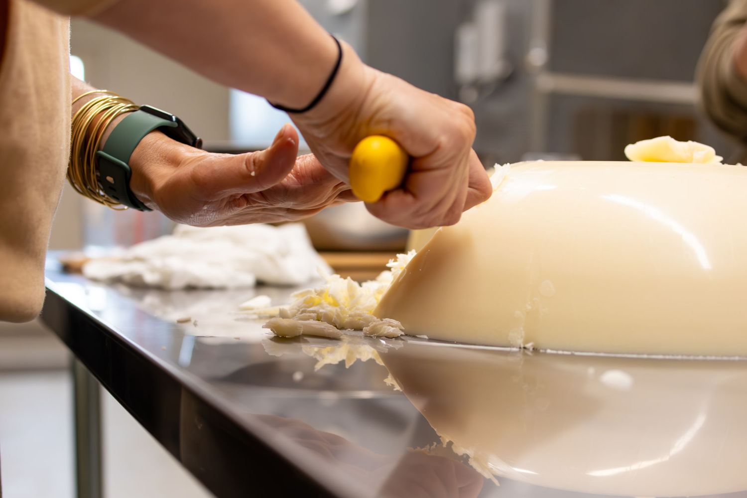 Hands preparing food ingredients on a dark countertop in a kitchen setting.