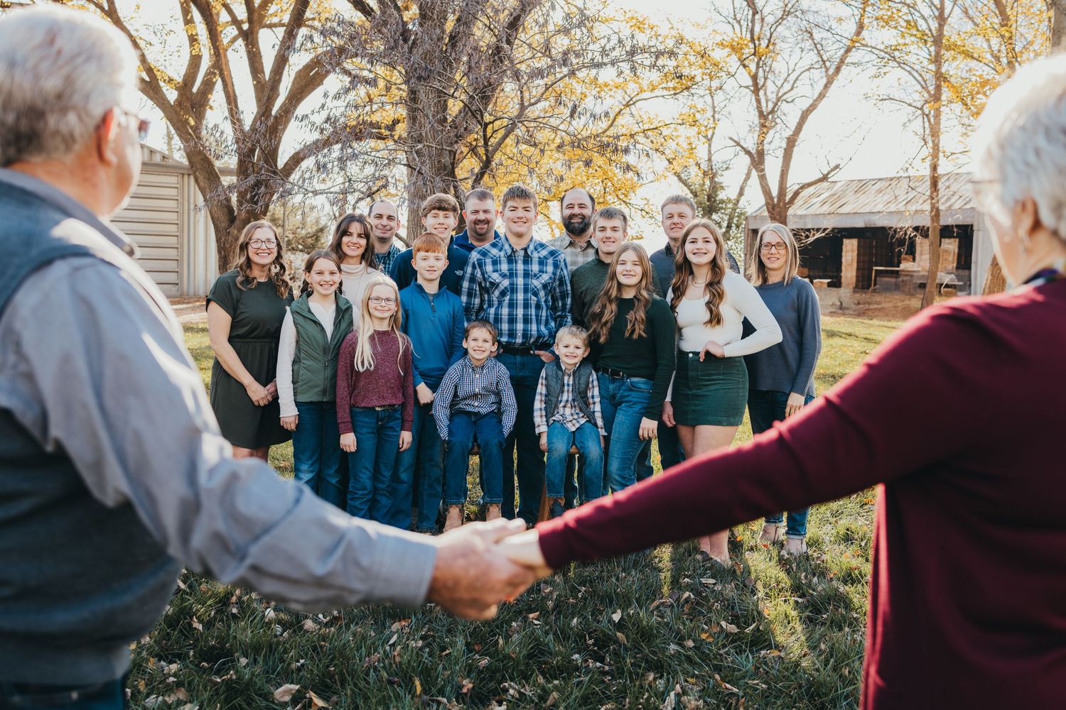 A multigenerational family forms a circle while holding hands outdoors.