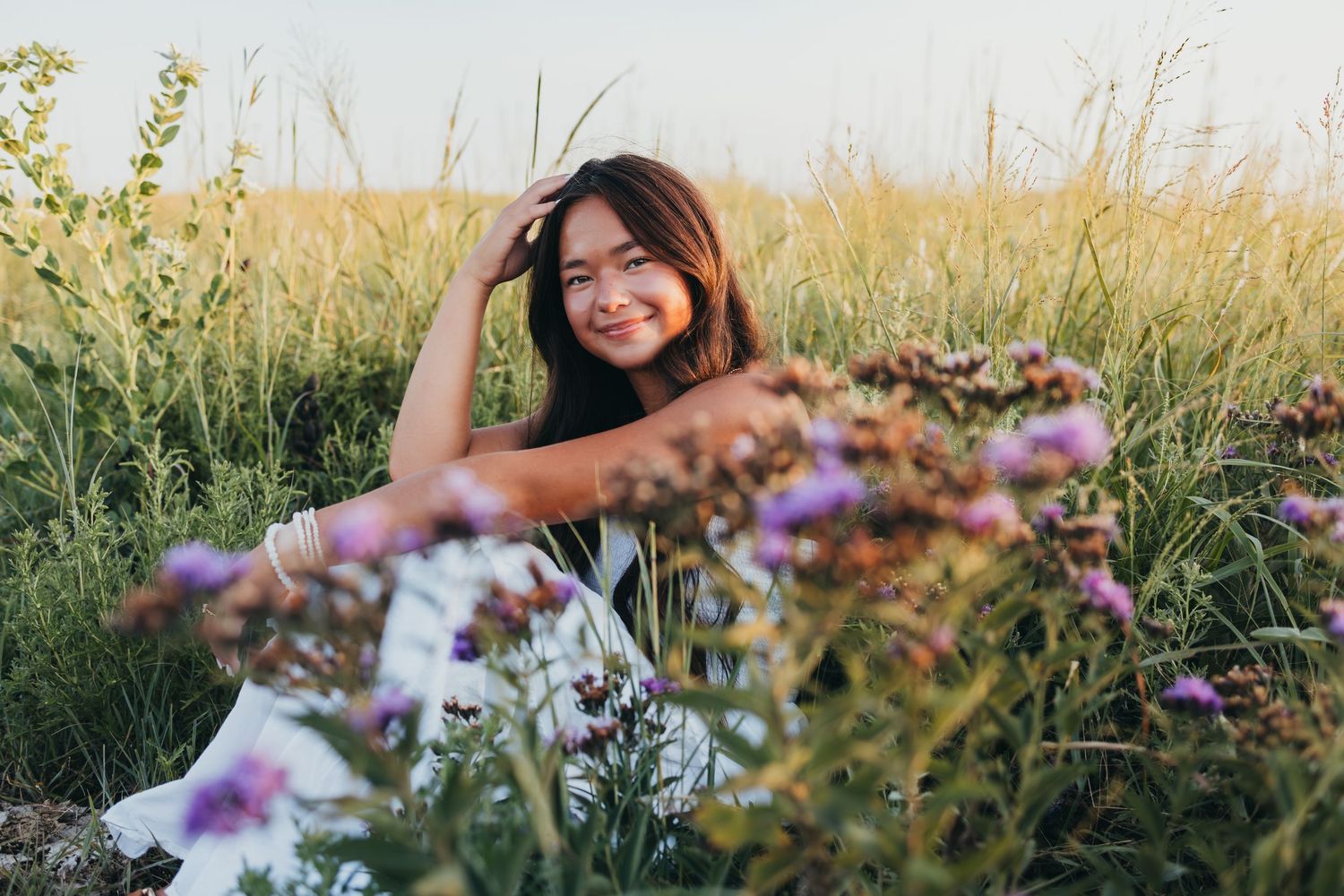 Wildflowers and tall grass sway in a golden meadow during sunset, creating a dreamy natural landscape.