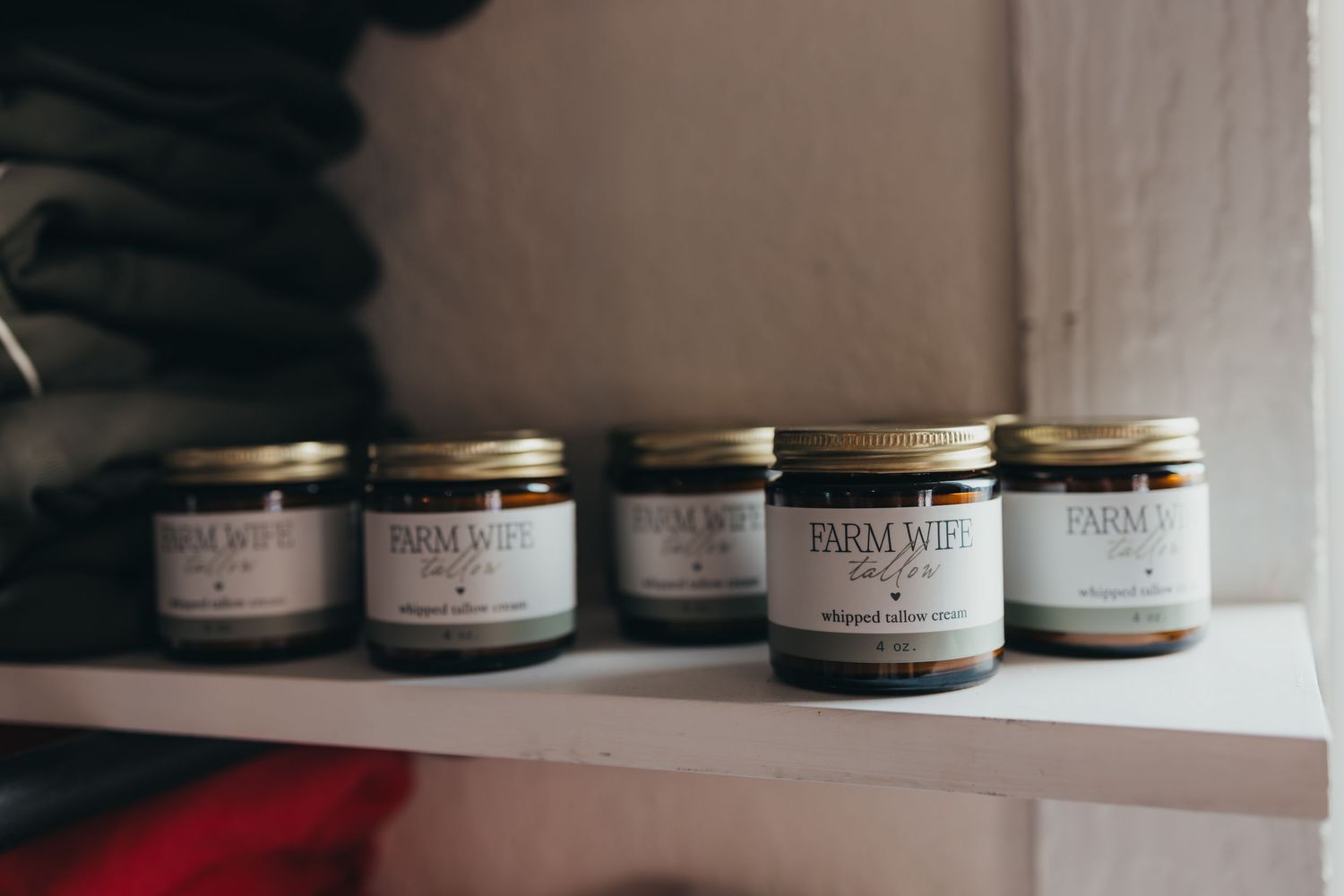 Row of artisanal jars with labeled products lined up neatly on a white shelf.