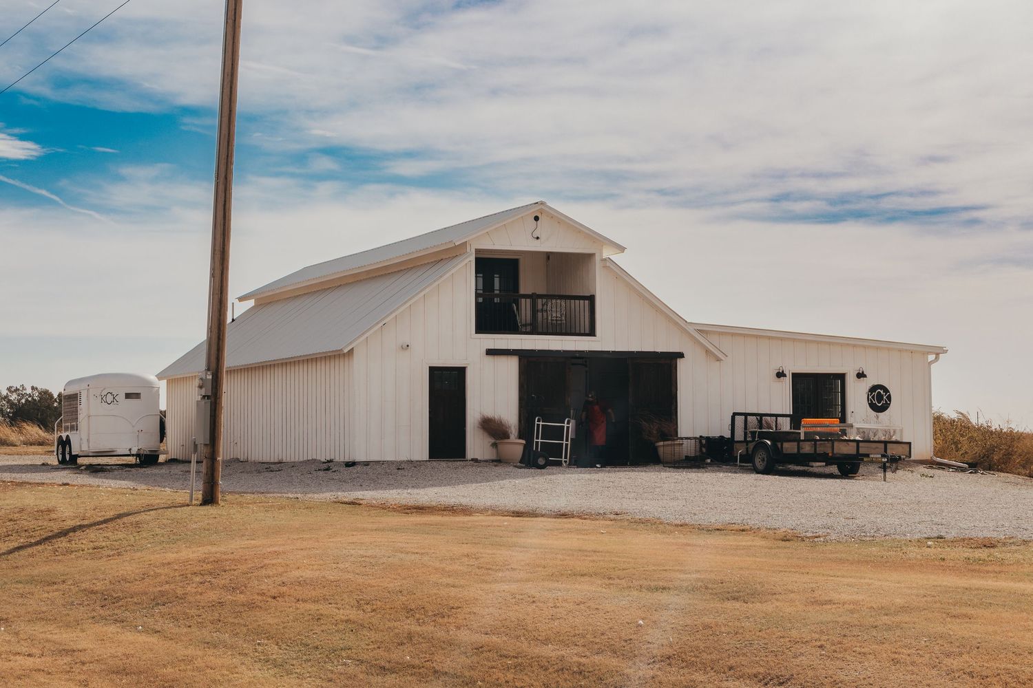 Modern white barn-style building with black trim on a rural property.