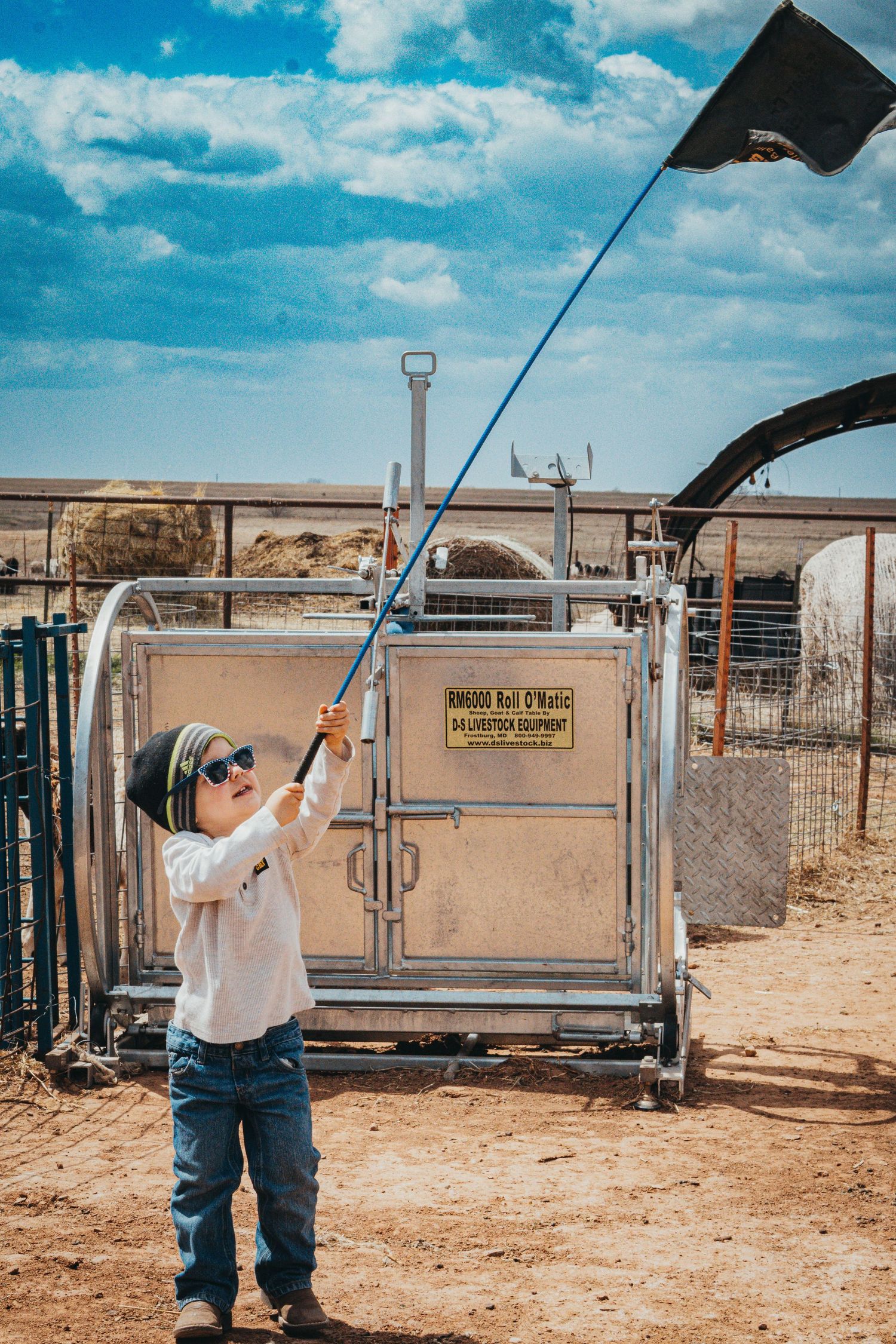 Young child using flag equipment in a dusty livestock arena.