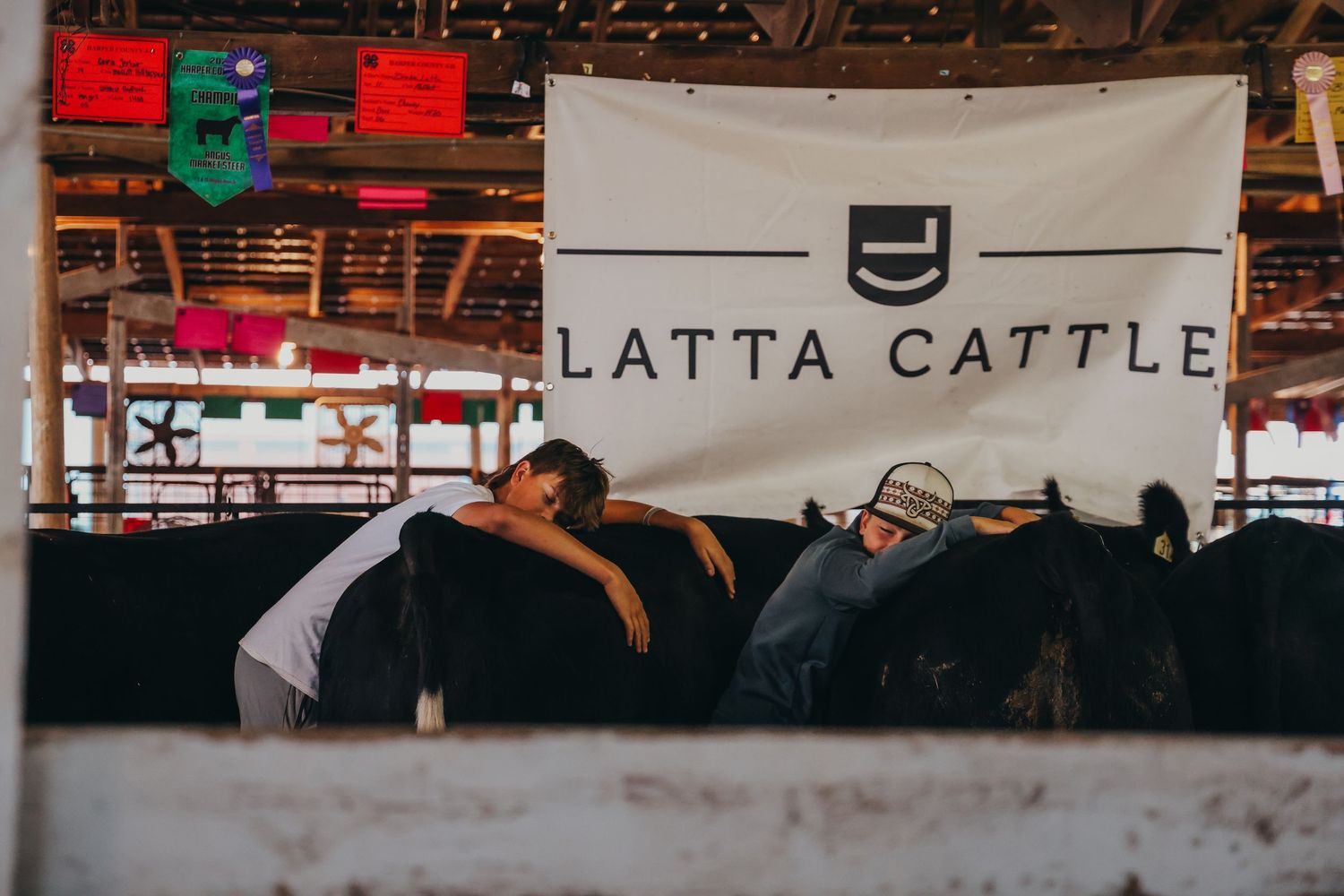 Three cowboys take a nap beneath a Latta Cattle banner at a livestock show.
