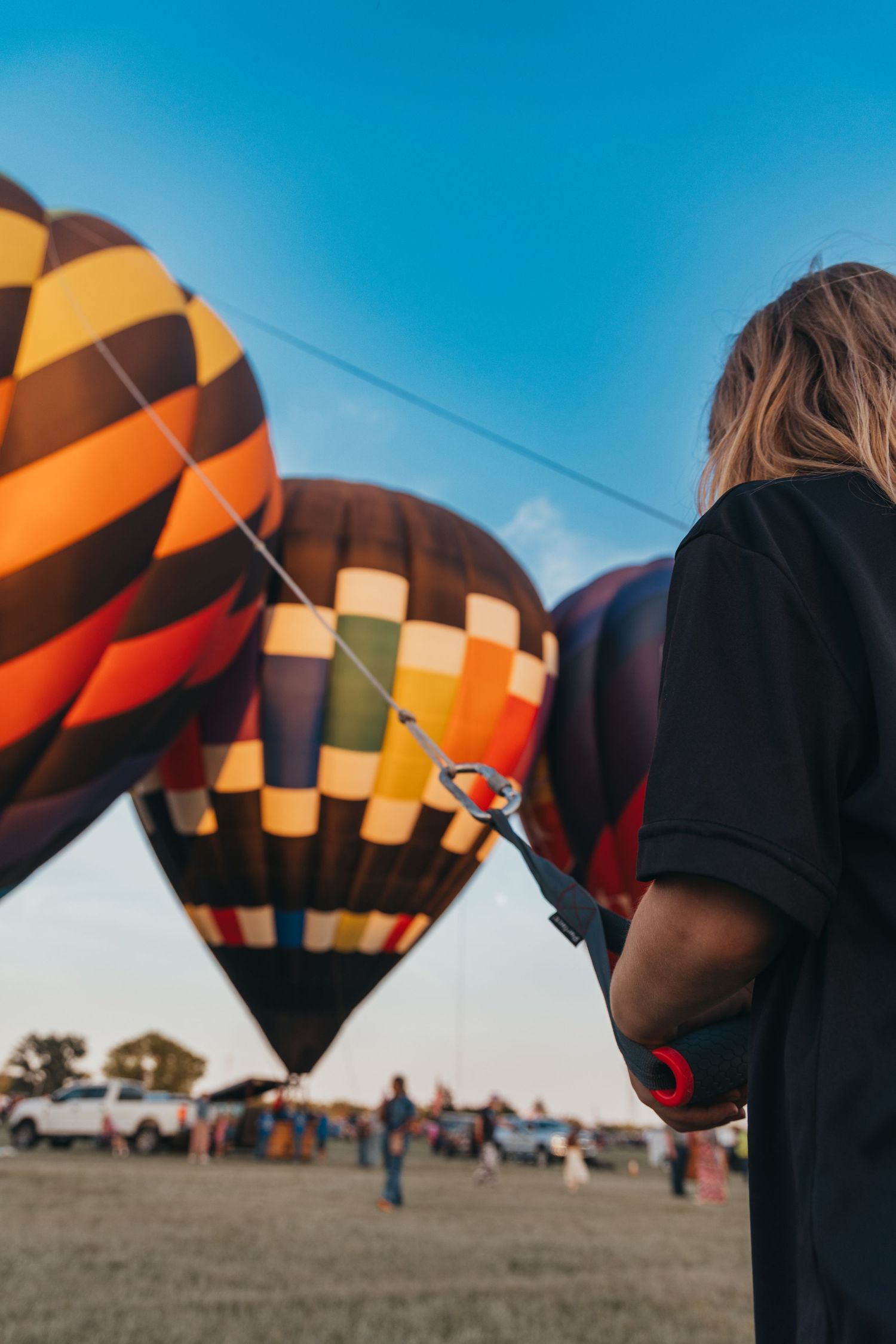 View of multiple hot air balloons from behind an observer at a balloon festival.