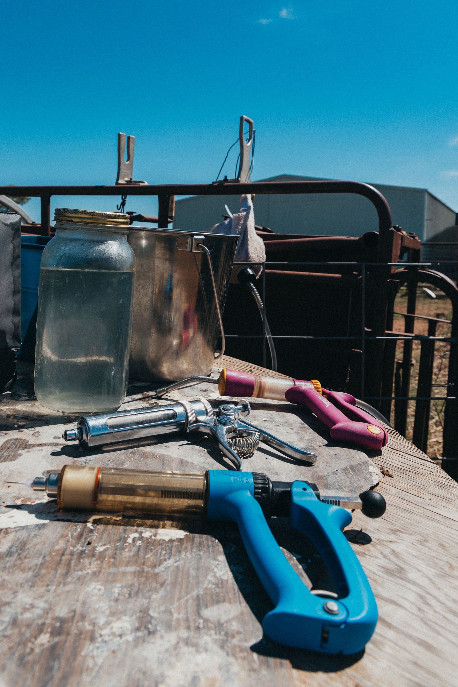 Farm tools and equipment laid out on wooden surface outdoors.