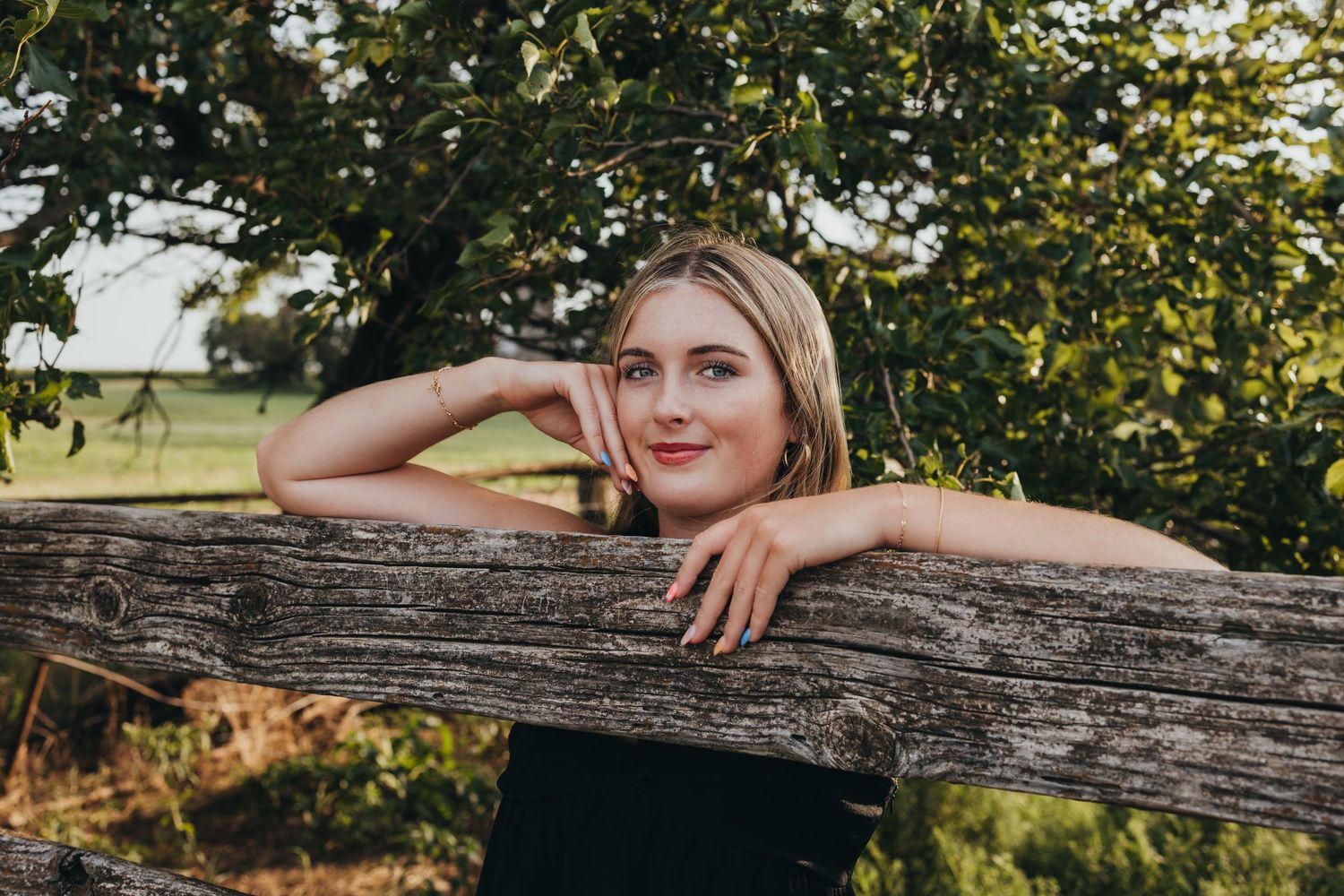 A rustic wooden fence provides a natural backdrop for outdoor portraits in golden evening sunlight.
