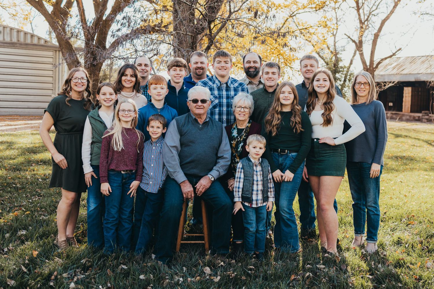 Extended family members gather for a group photo in a backyard setting during fall.
