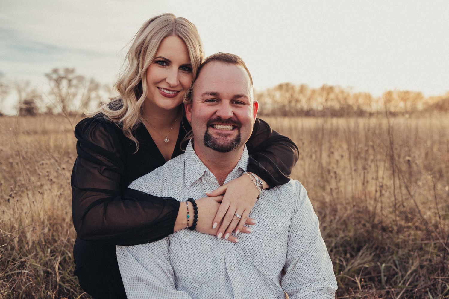 Romantic outdoor portrait of a couple embracing in a golden field at sunset.