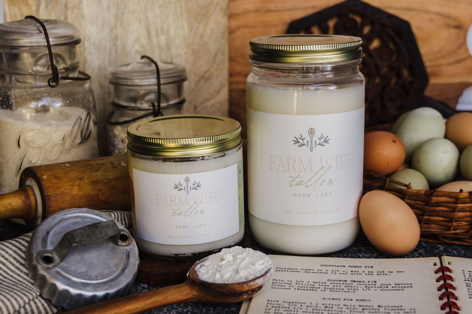 Rustic farmhouse display of mason jars filled with flour and baking ingredients alongside fresh eggs on wooden surface.