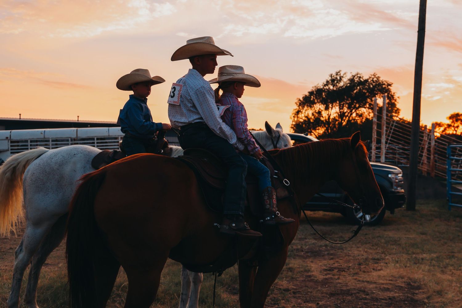 Riders on horseback silhouetted against sunset sky.