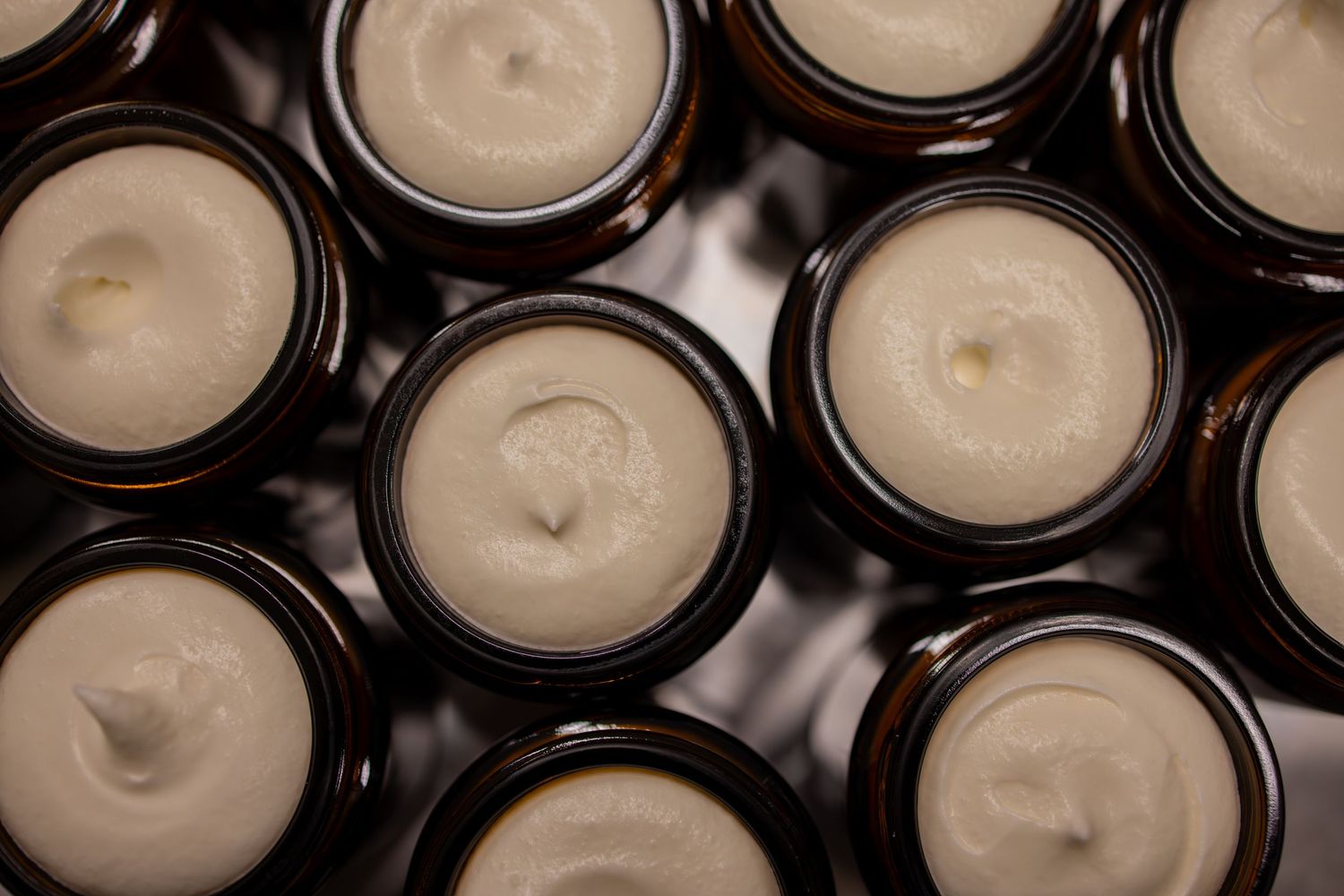 Overhead view of multiple filled amber glass jars with white cream products.