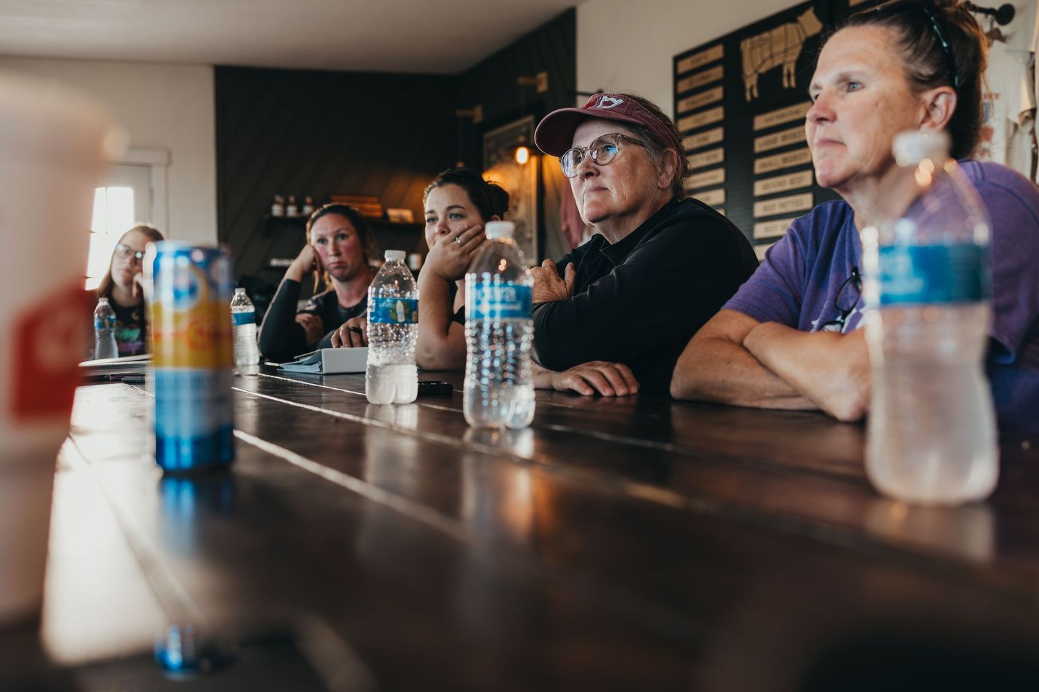 People seated at a long bar counter with water bottles and drinks.