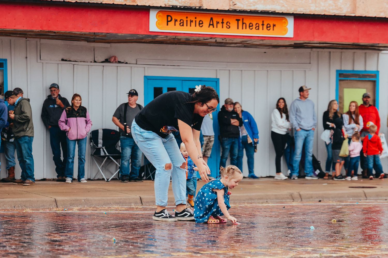 Two figures playing in the rain outside the Prairie Arts Theater.