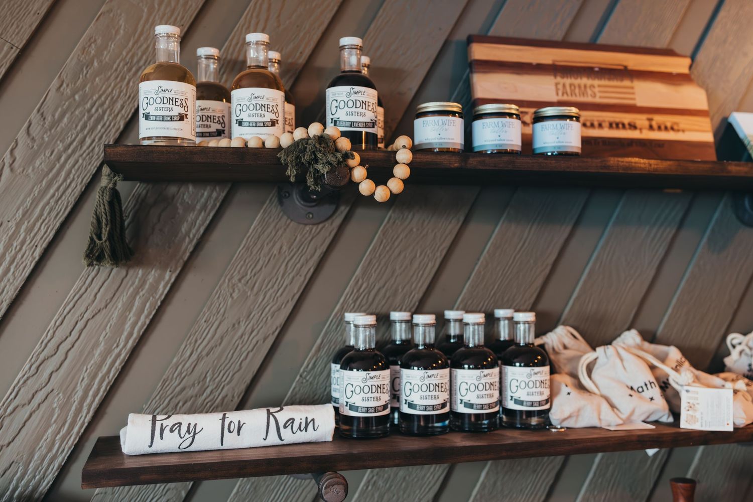 Rustic wooden shelves displaying small glass bottles with herb labels and decorative beaded accessories.