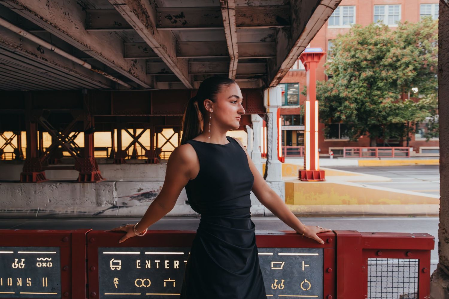 A person in black athletic wear performs a dance routine in an urban setting with red brick buildings in the background.