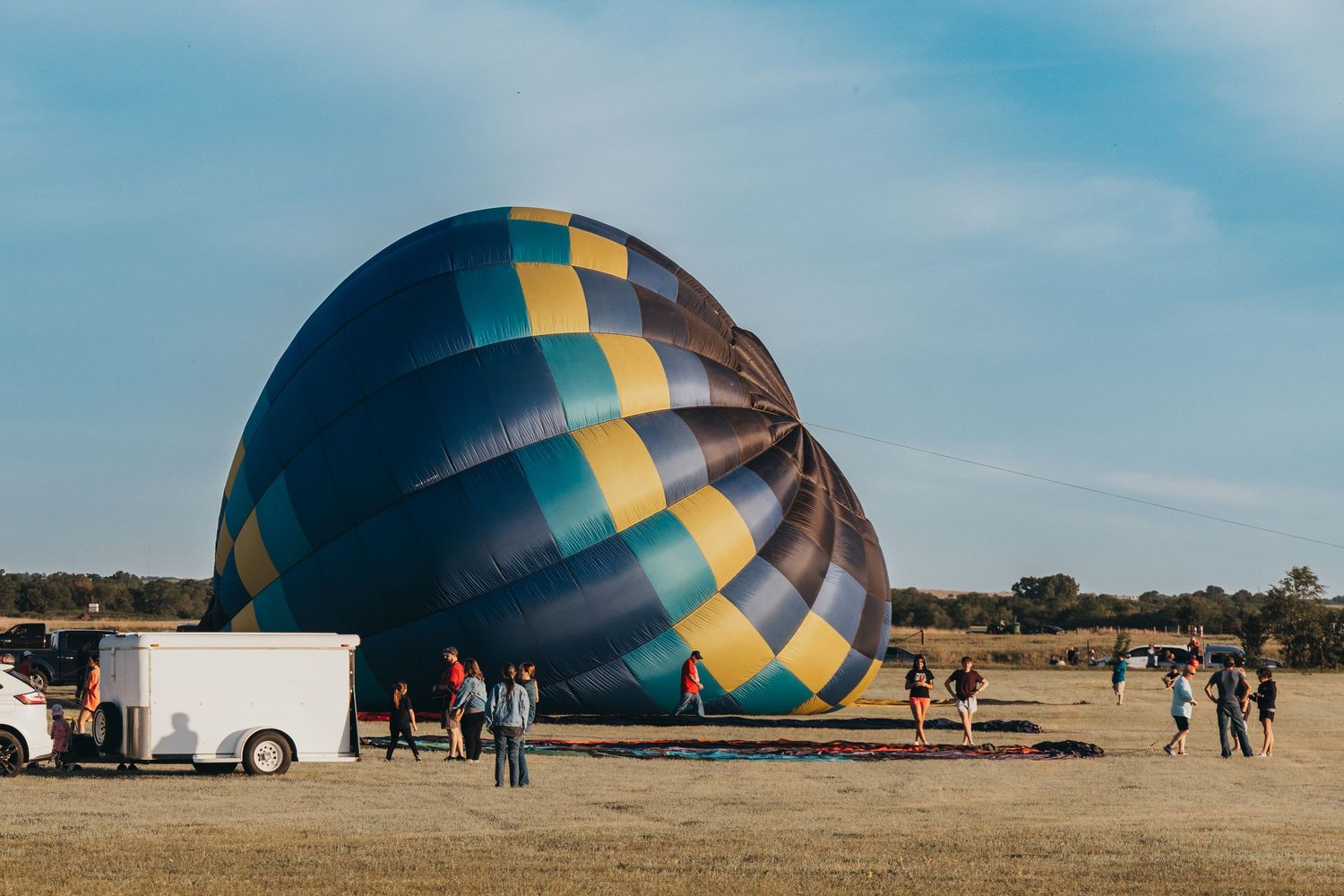 A large blue and yellow hot air balloon being inflated on the ground at a festival.