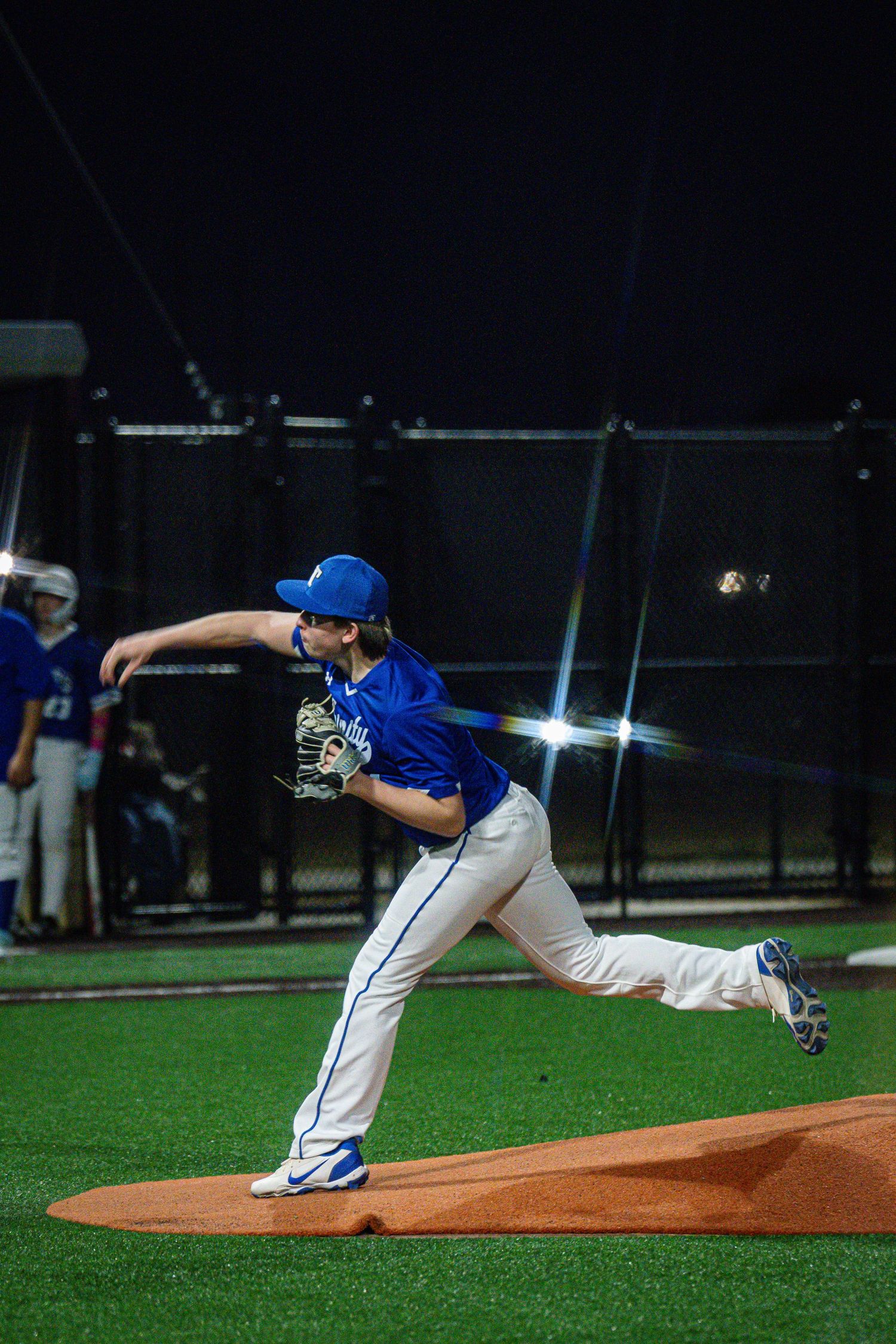 Baseball pitcher shown in sequential motion demonstrating proper throwing mechanics from the mound during a night game.