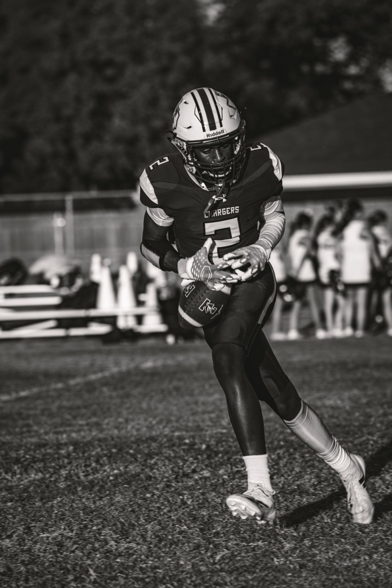 Black and white sequence of a football player running with the ball on a grass field during a game.