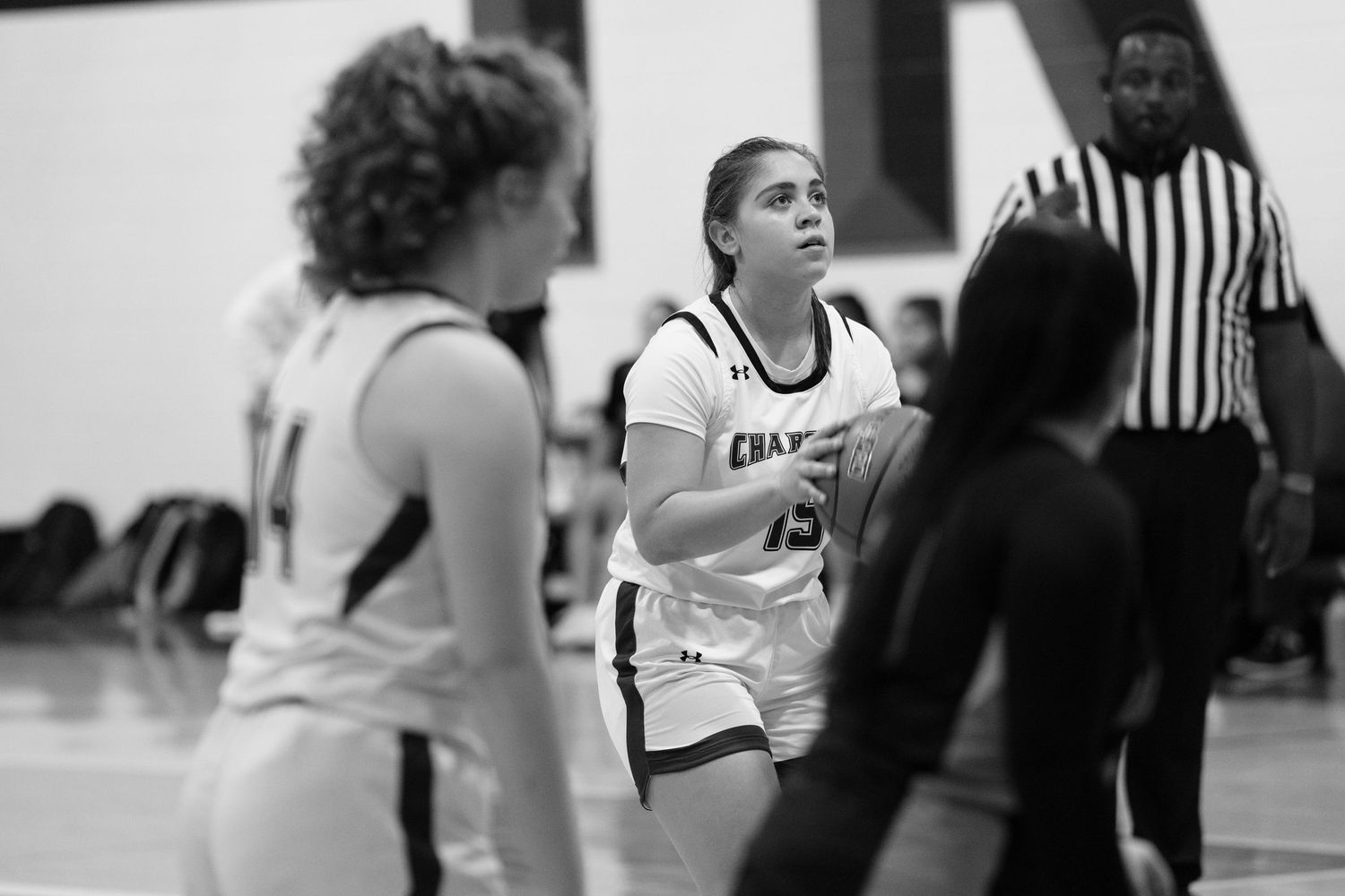 Basketball players in black and white uniforms compete during a competitive indoor game with referees present.