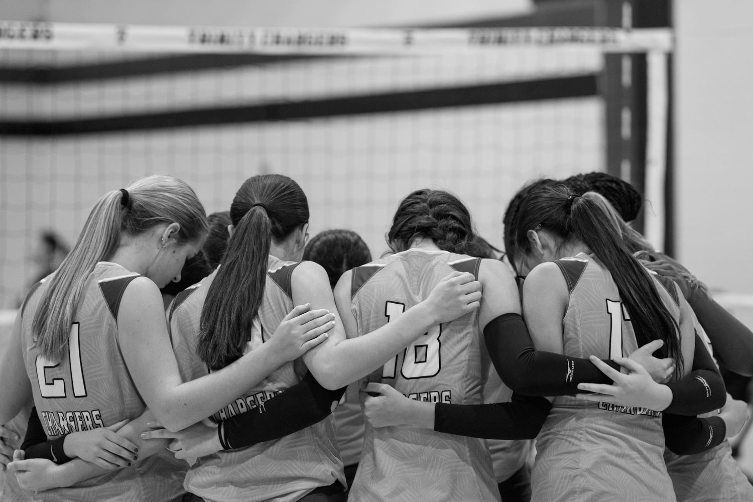 Sports team huddles together with arms around each other in a show of unity before a game.