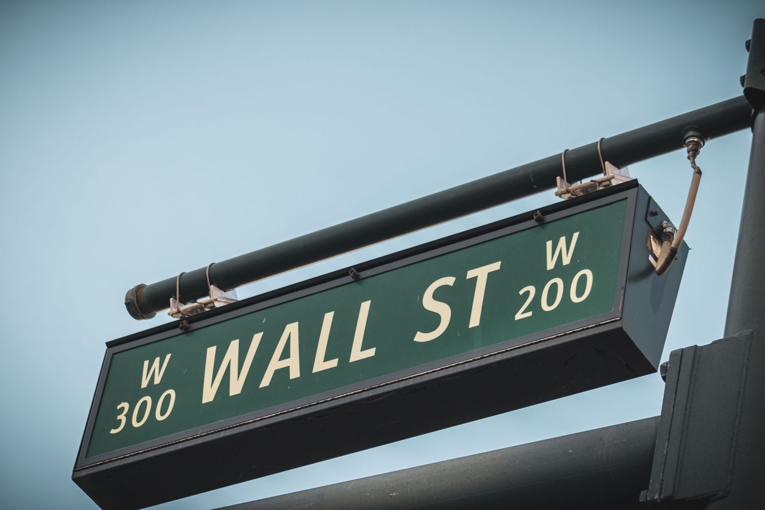 Wall Street intersection sign showing West 200 block against pale blue sky.