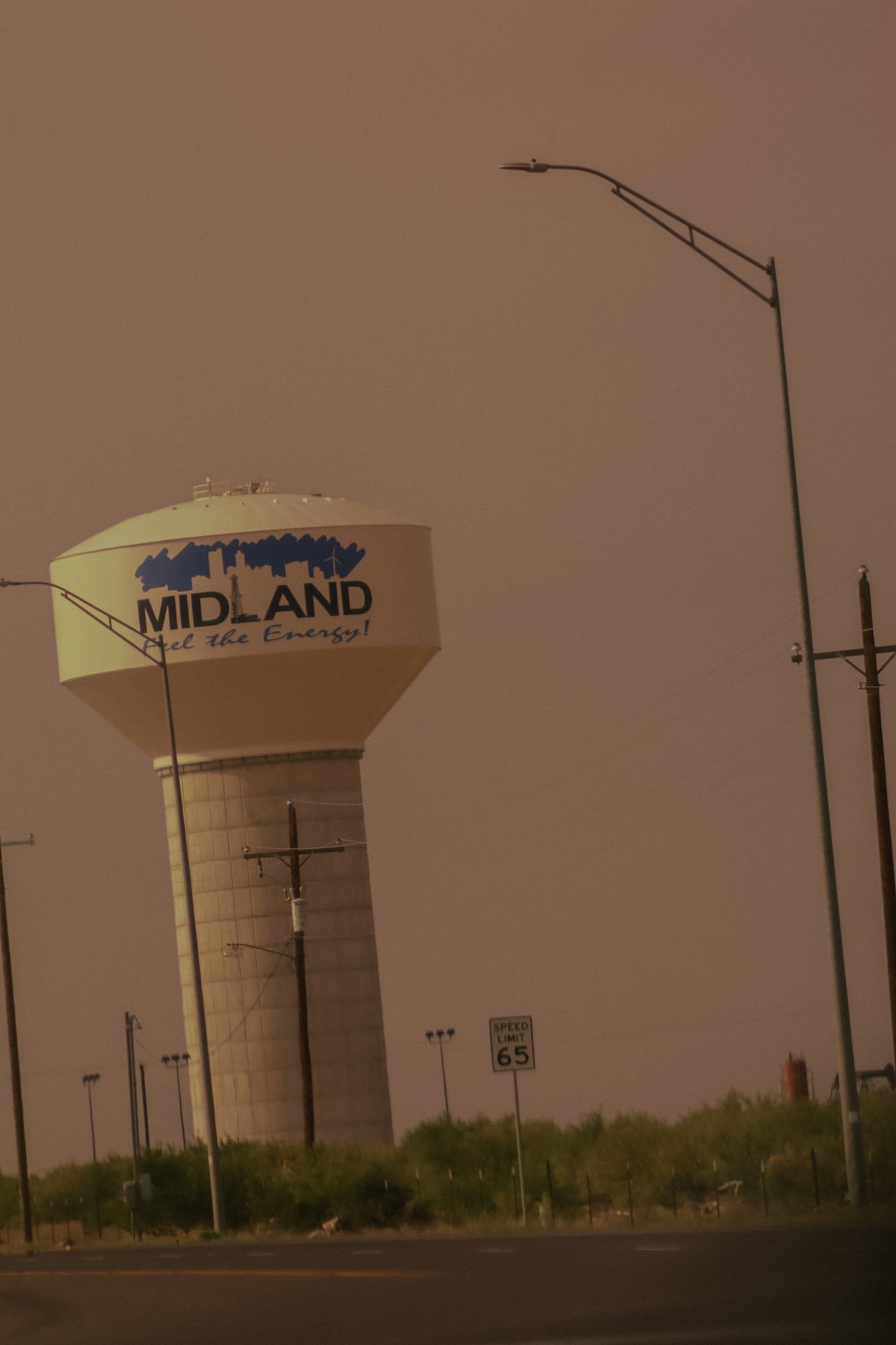 Water tower with Midland text visible against a dusty brown sky.