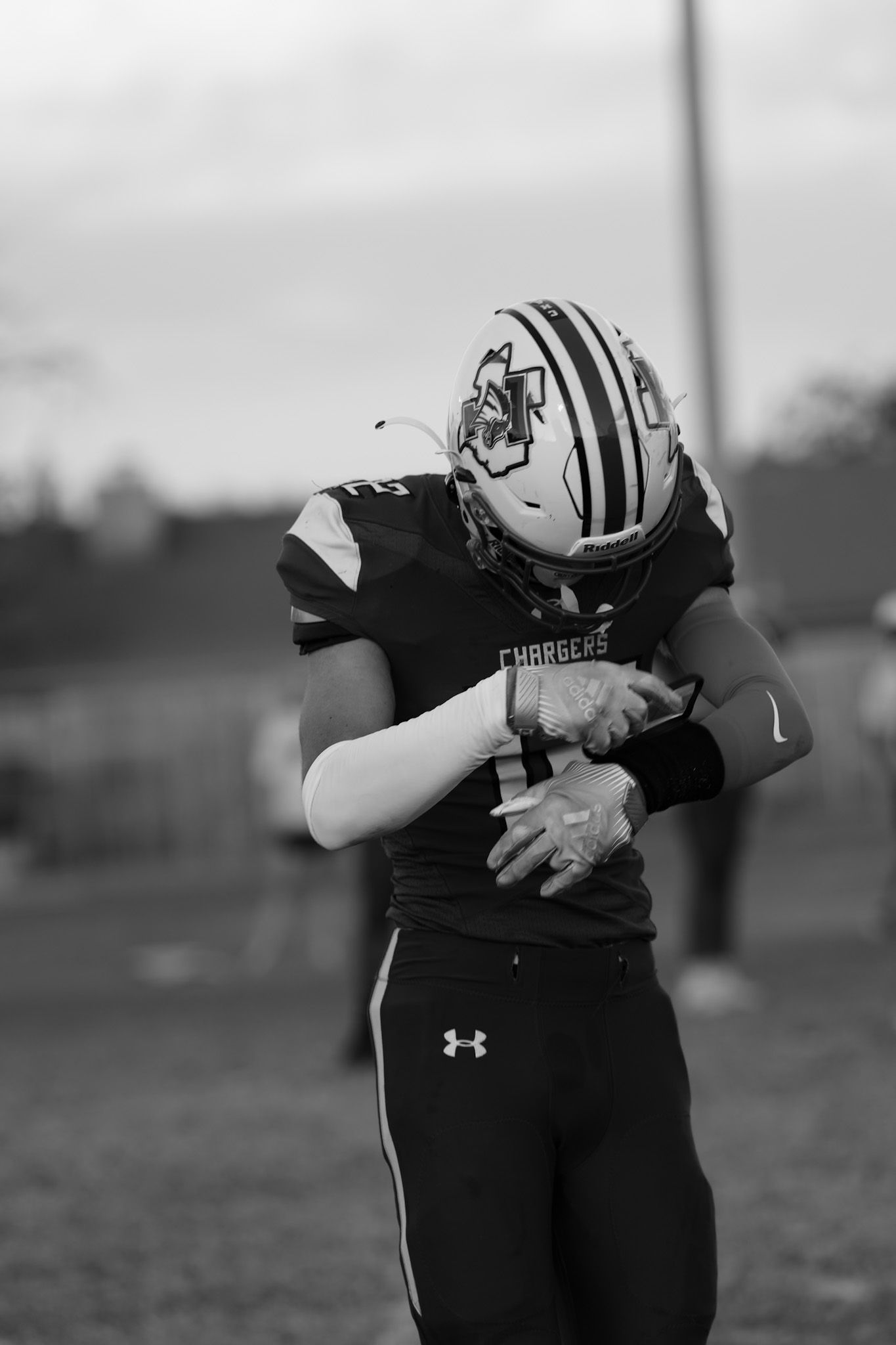 Close-up of football player's torso in black Under Armour uniform holding ball against chest.