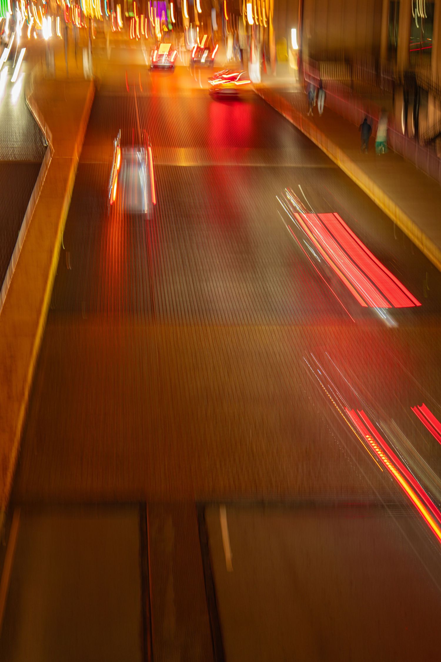 Long exposure photo of red taillights creating light trails on a dark street at night.